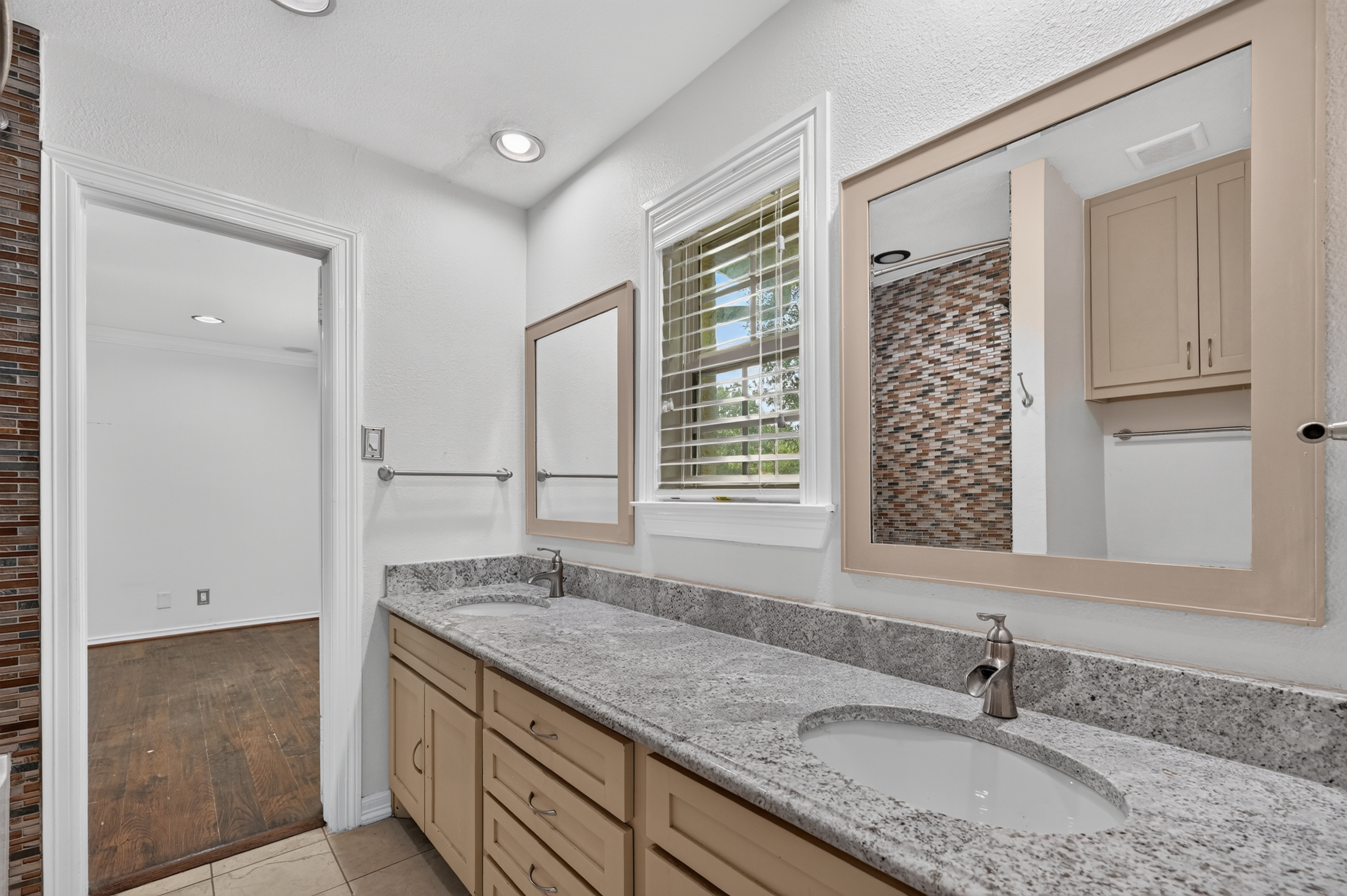 Ensuite bath with dual vanity, granite countertops, and mosaic stone walk-in shower