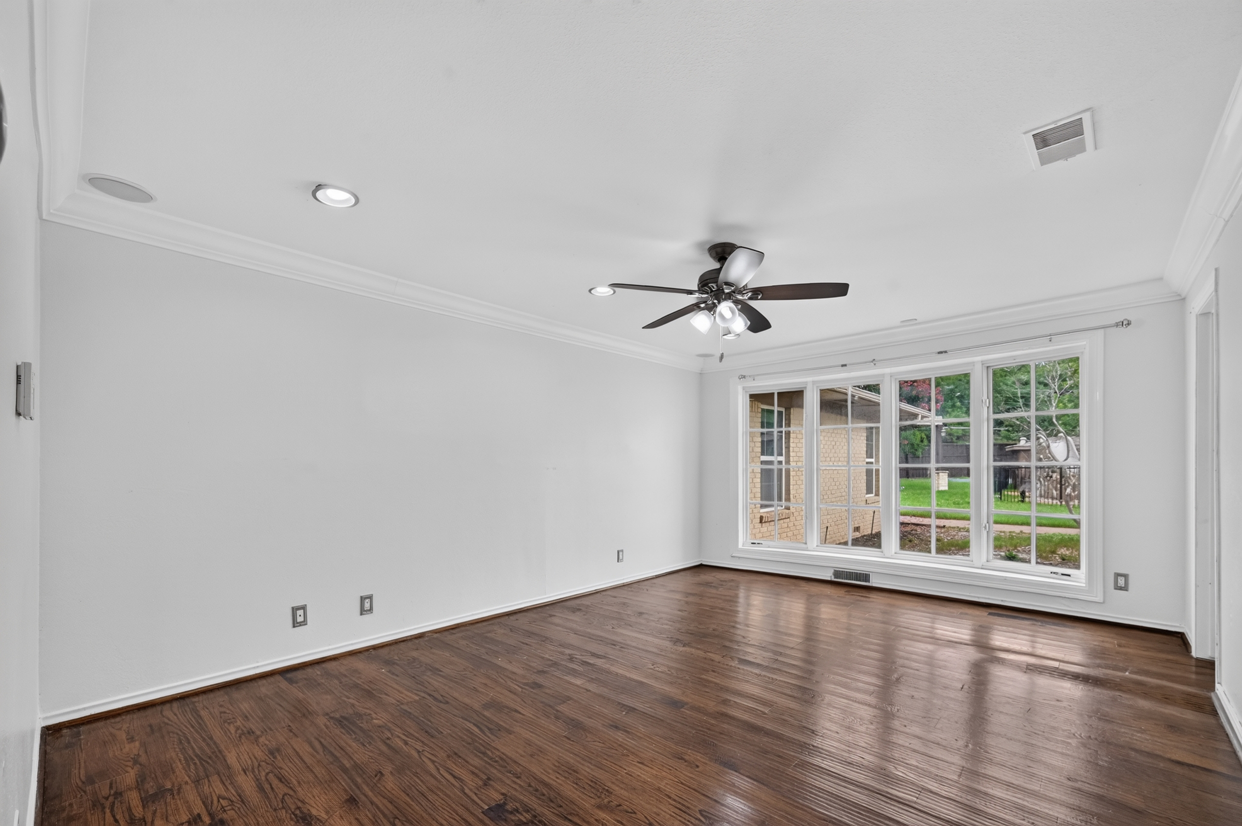Expansive bedroom suite with rich hardwood floors, recessed lighting, and picturesque bay windows