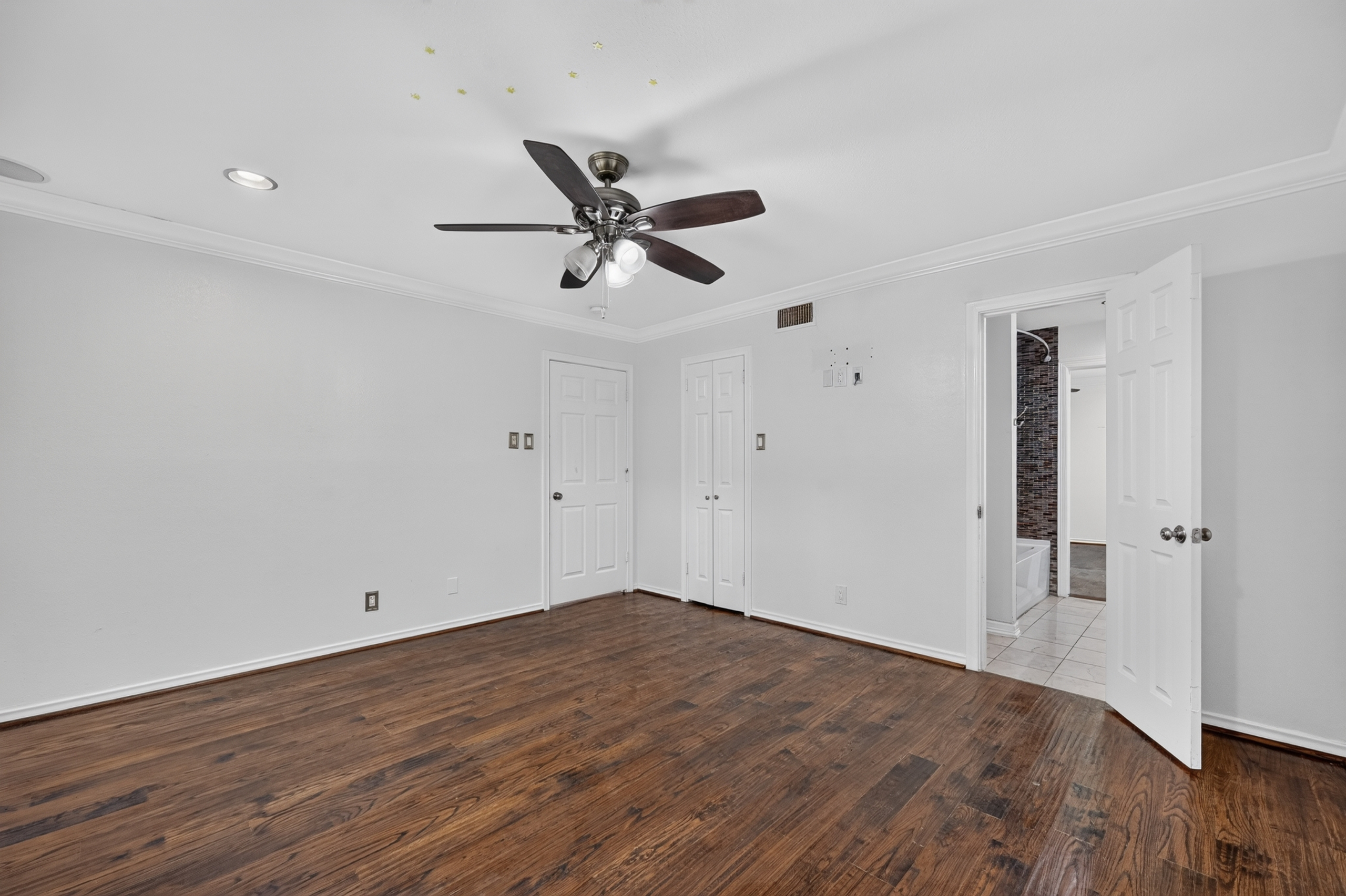 Warm hardwood bedroom view looking toward private ensuite bath with artisan tiled shower