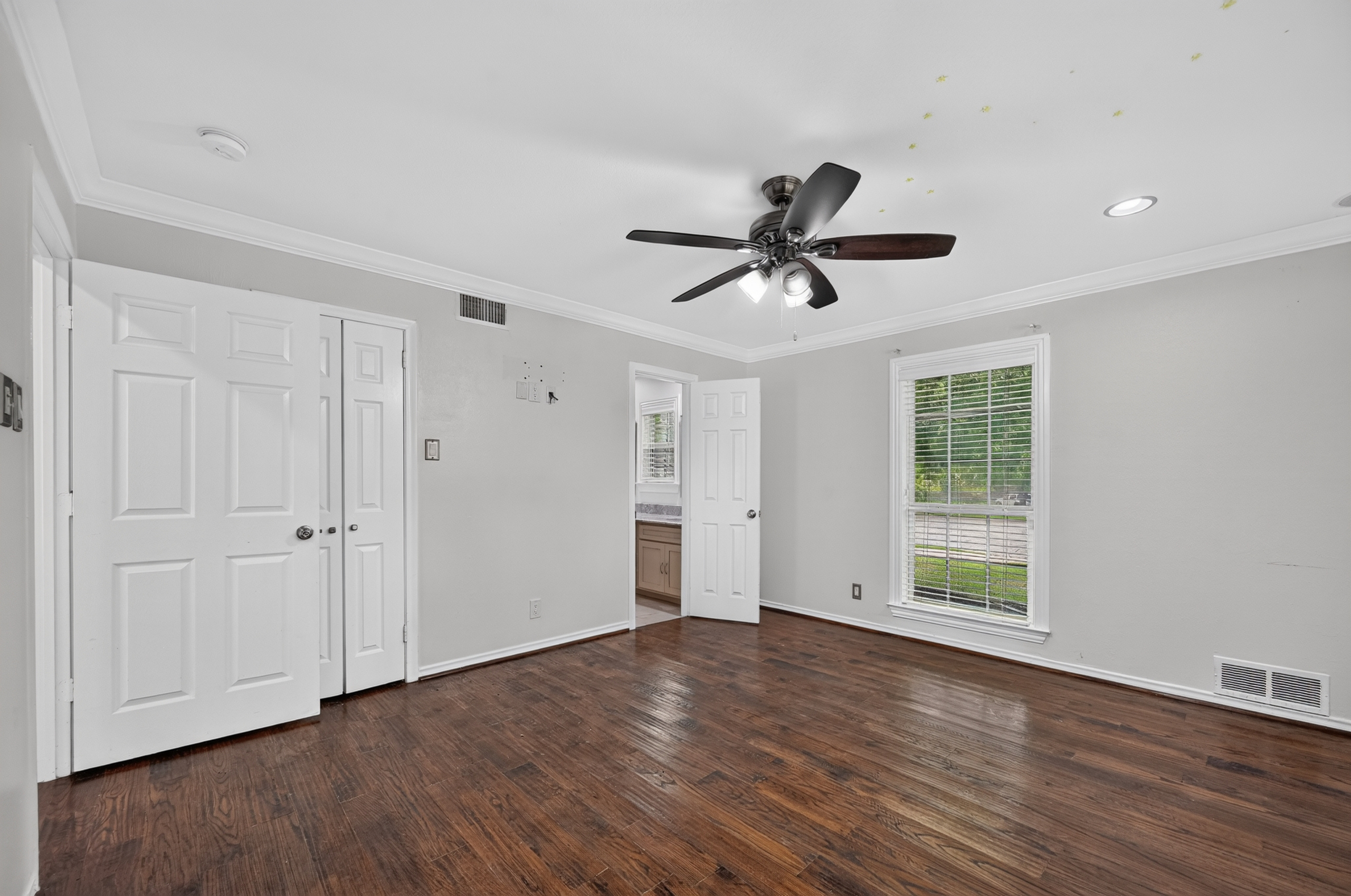 Bedroom suite featuring double closets, crown molding, and adjoining private bath access