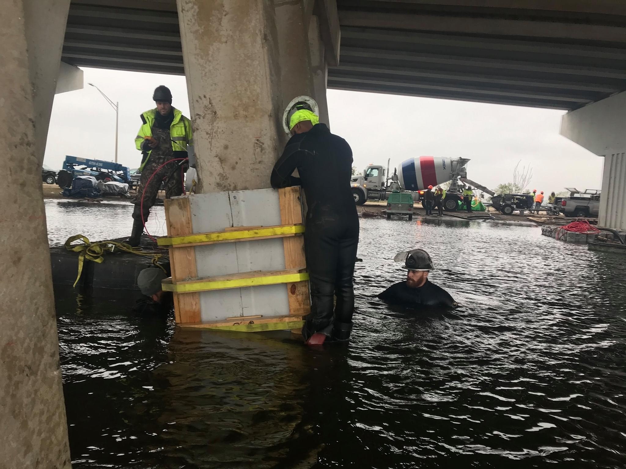 Cuadrilla de buceo instalando encamisados de pilotes en puente carretero