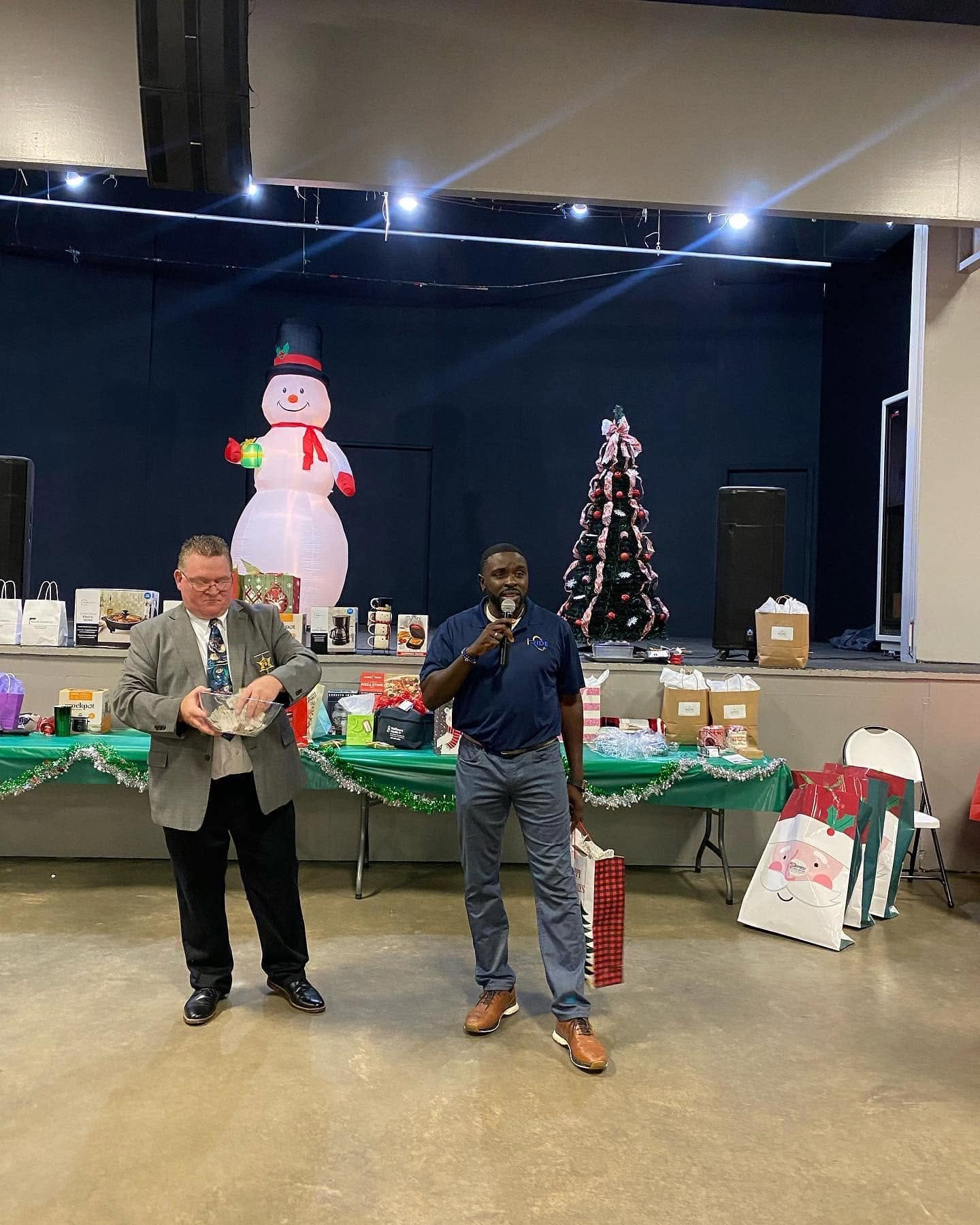 Cleveland Auzenne speaking at a holiday community event raffle stage.