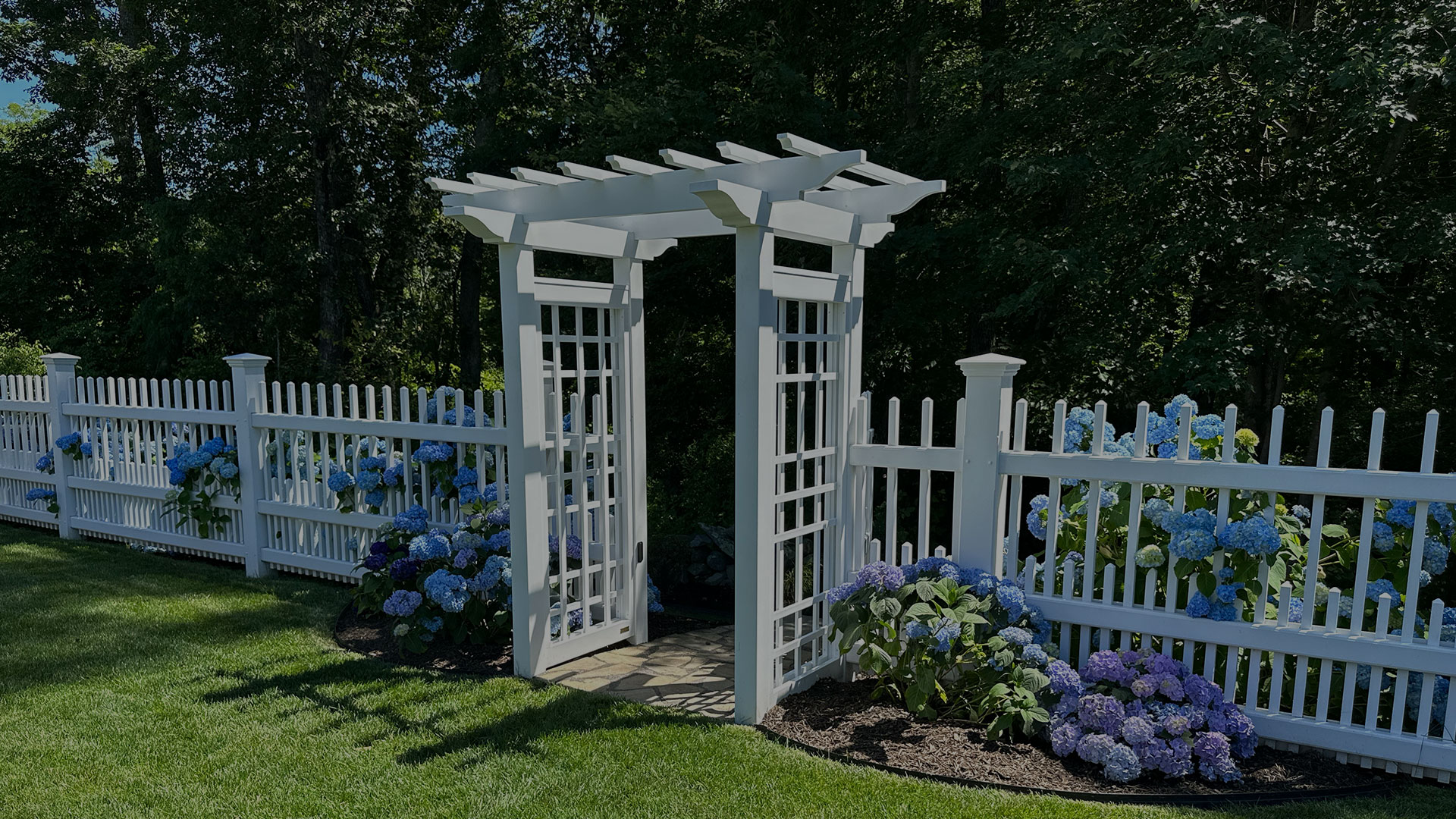 White garden arbor and hydrangea gate by IVE Landscaping