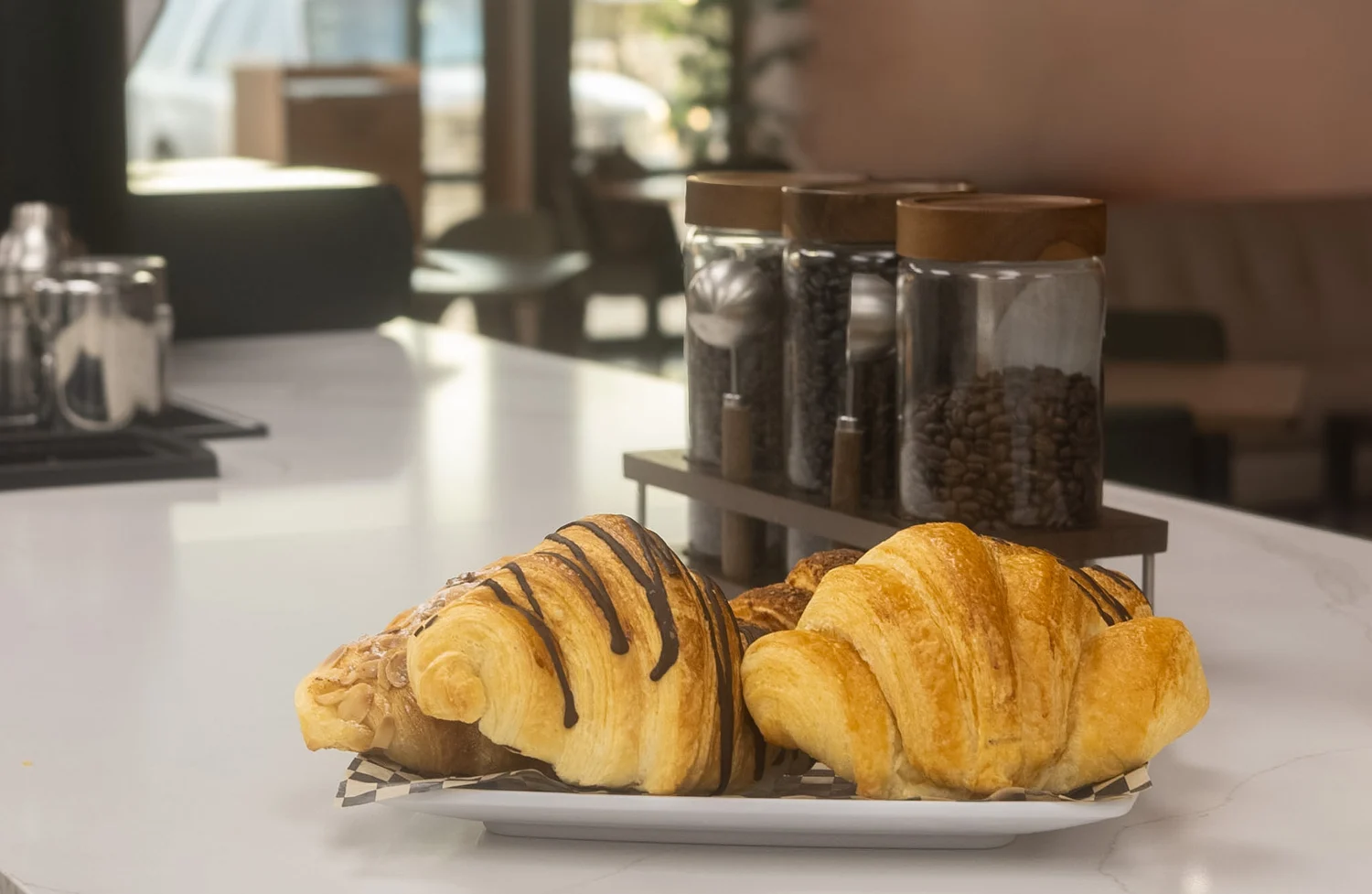 Two golden croissants, one with a chocolate drizzle