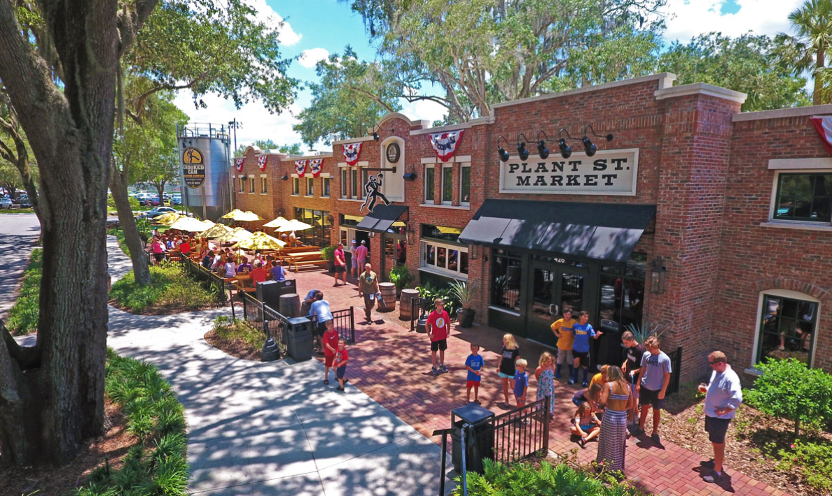 Elevated view of Plant St. Market brick plaza, outdoor patio with yellow umbrellas and live oaks