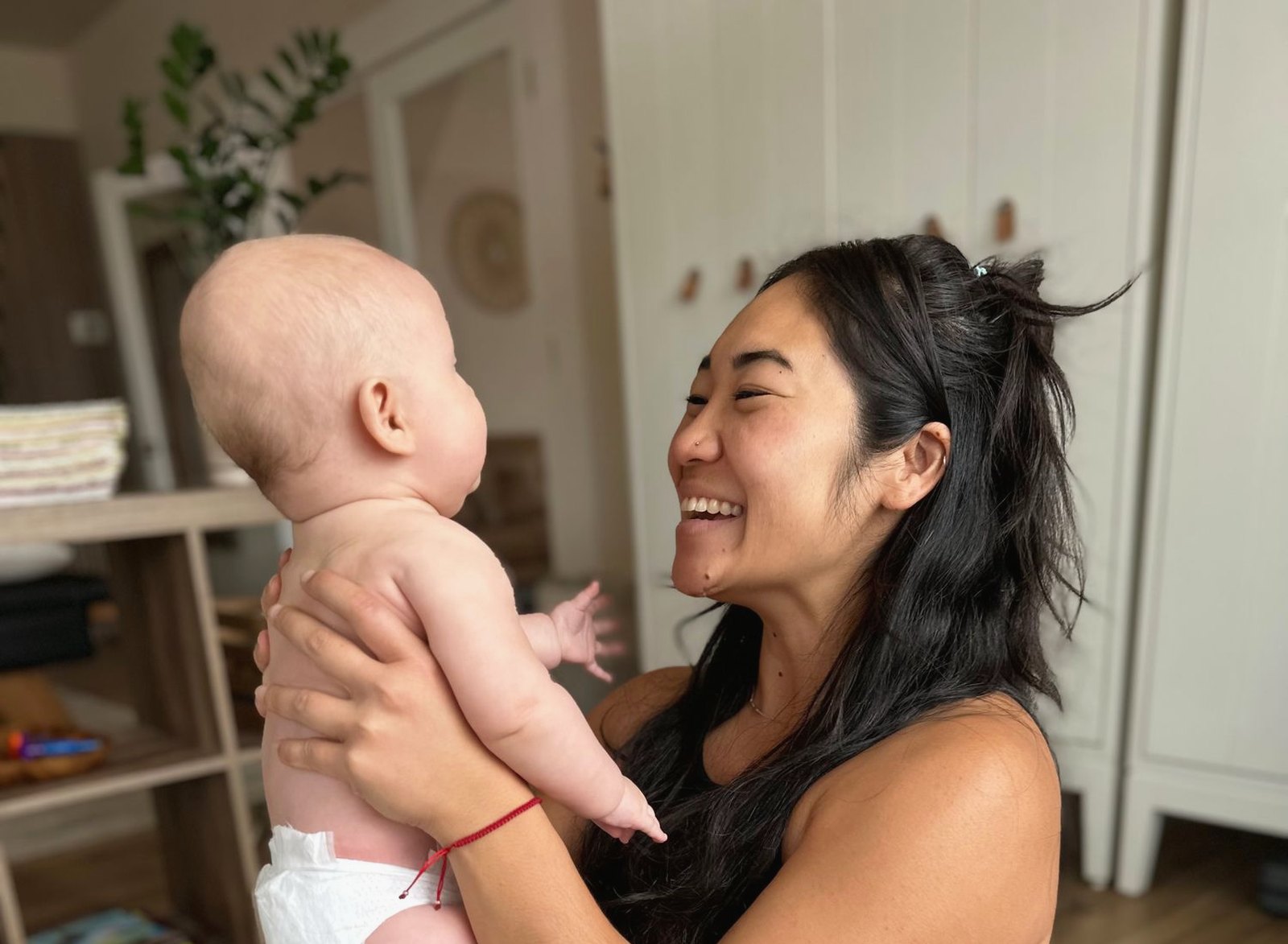 Dr. Kaitlyn Shikada laughing as she lifts a happy baby