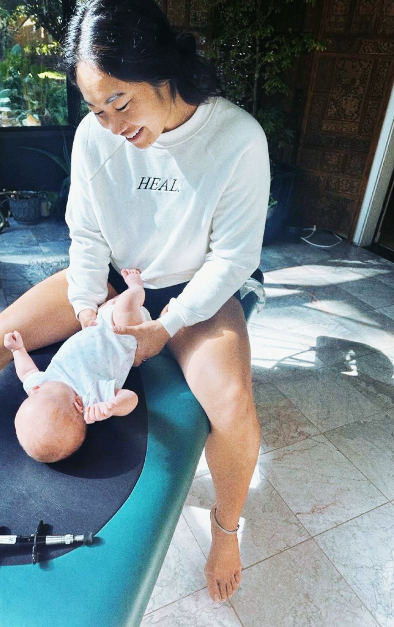 Dr. Kaitlyn Shikada smiling as she gently cares for a newborn in a sunlit room