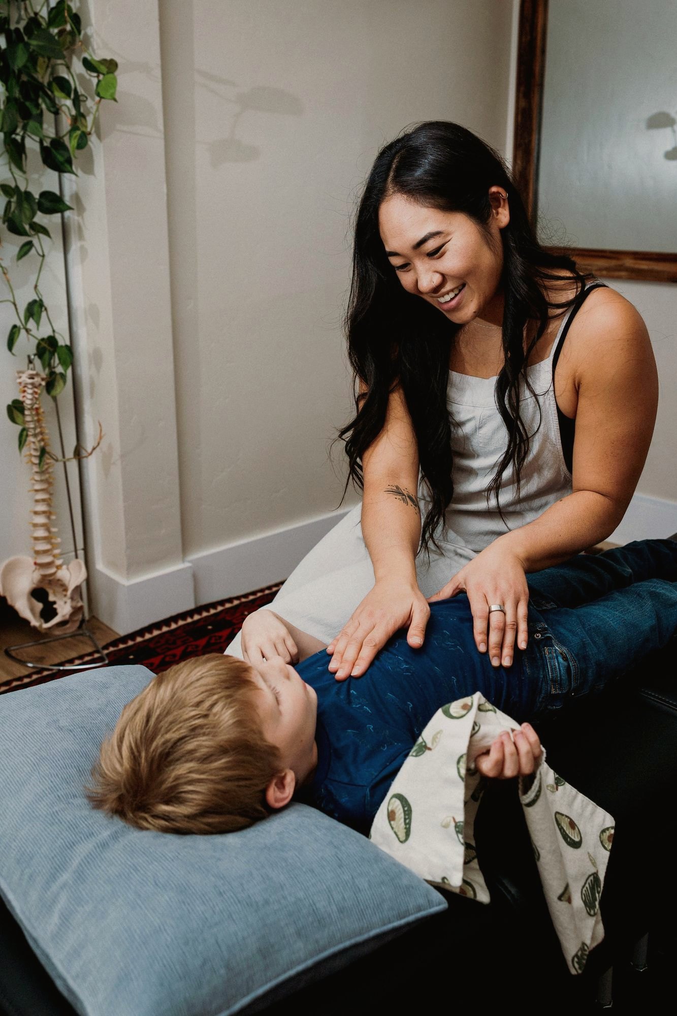 Dr. Kaitlyn Shikada laughing with a young child resting on the adjusting table