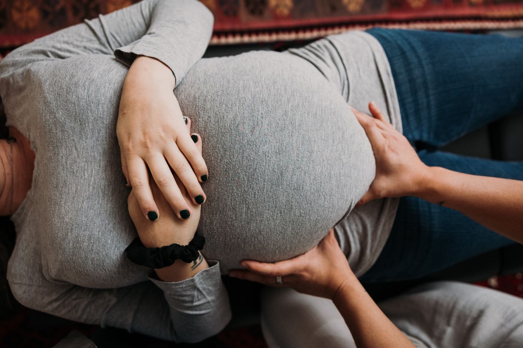 Dr. Kaitlyn's hands resting gently on an expecting mother's belly during prenatal care