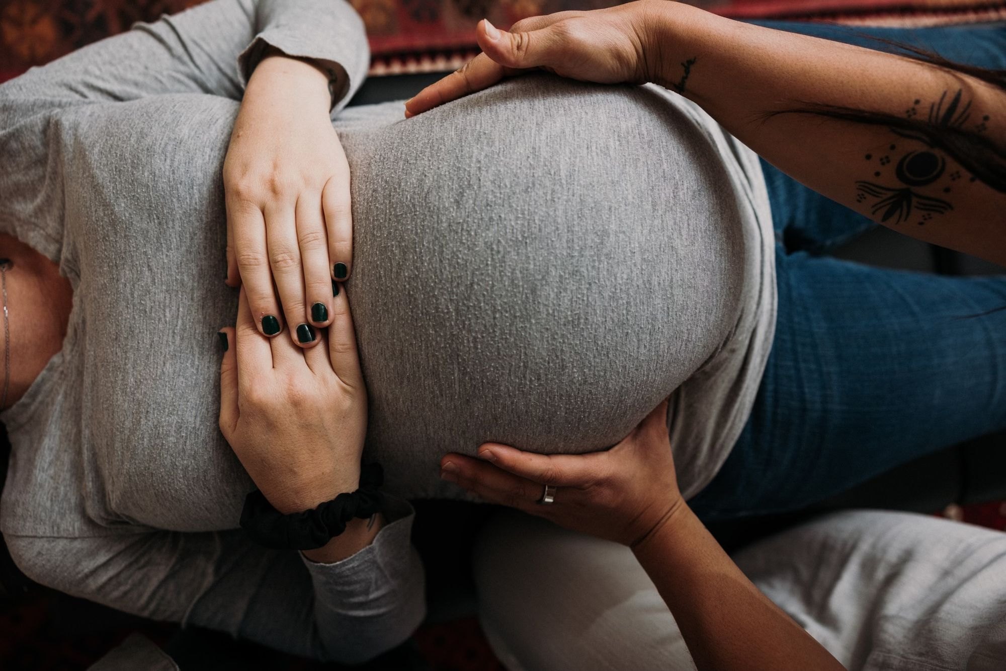 Dr. Kaitlyn's hands resting gently on an expecting mother's belly