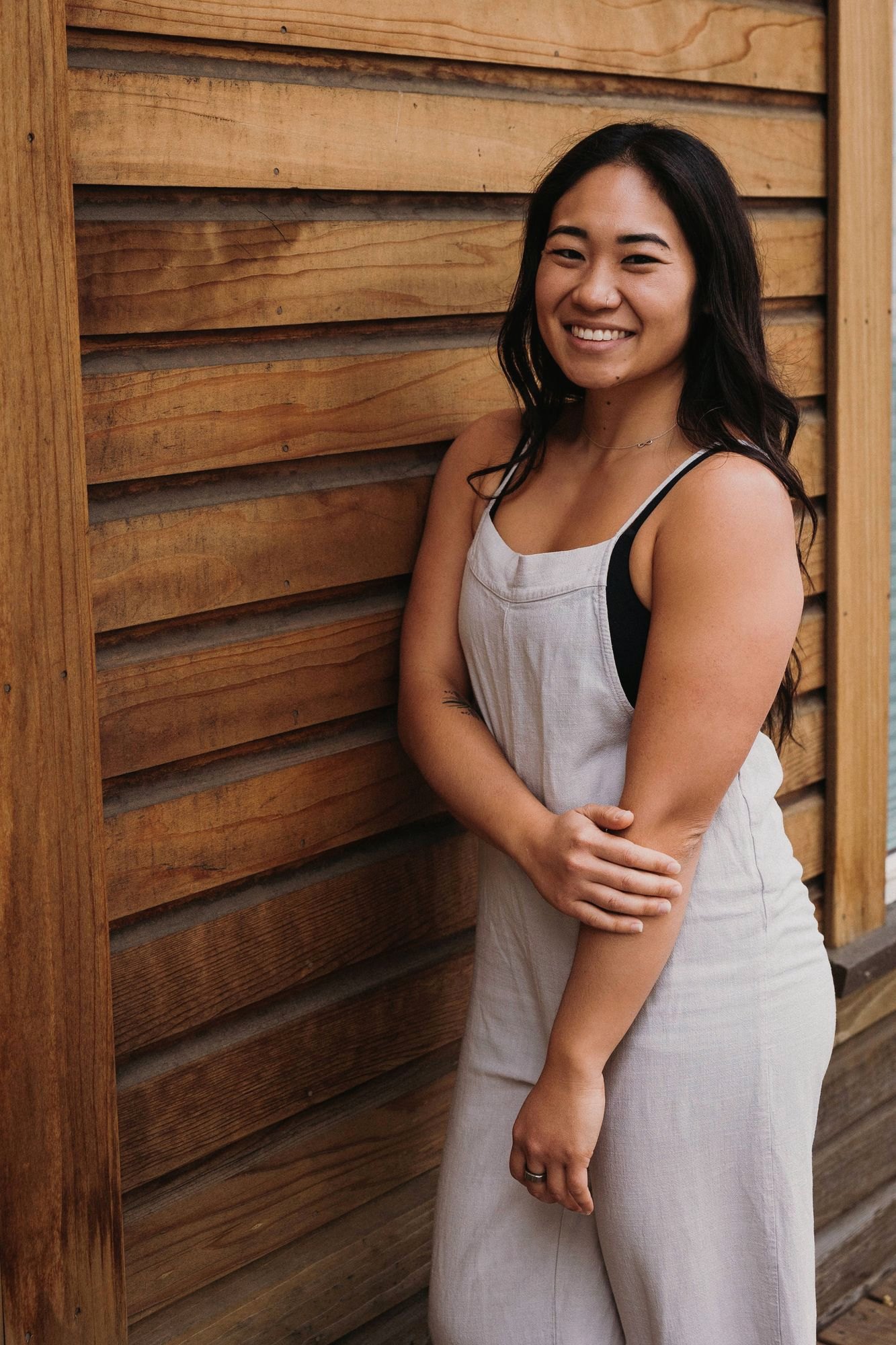 Dr. Kaitlyn Shikada smiling, relaxed against a warm wood wall