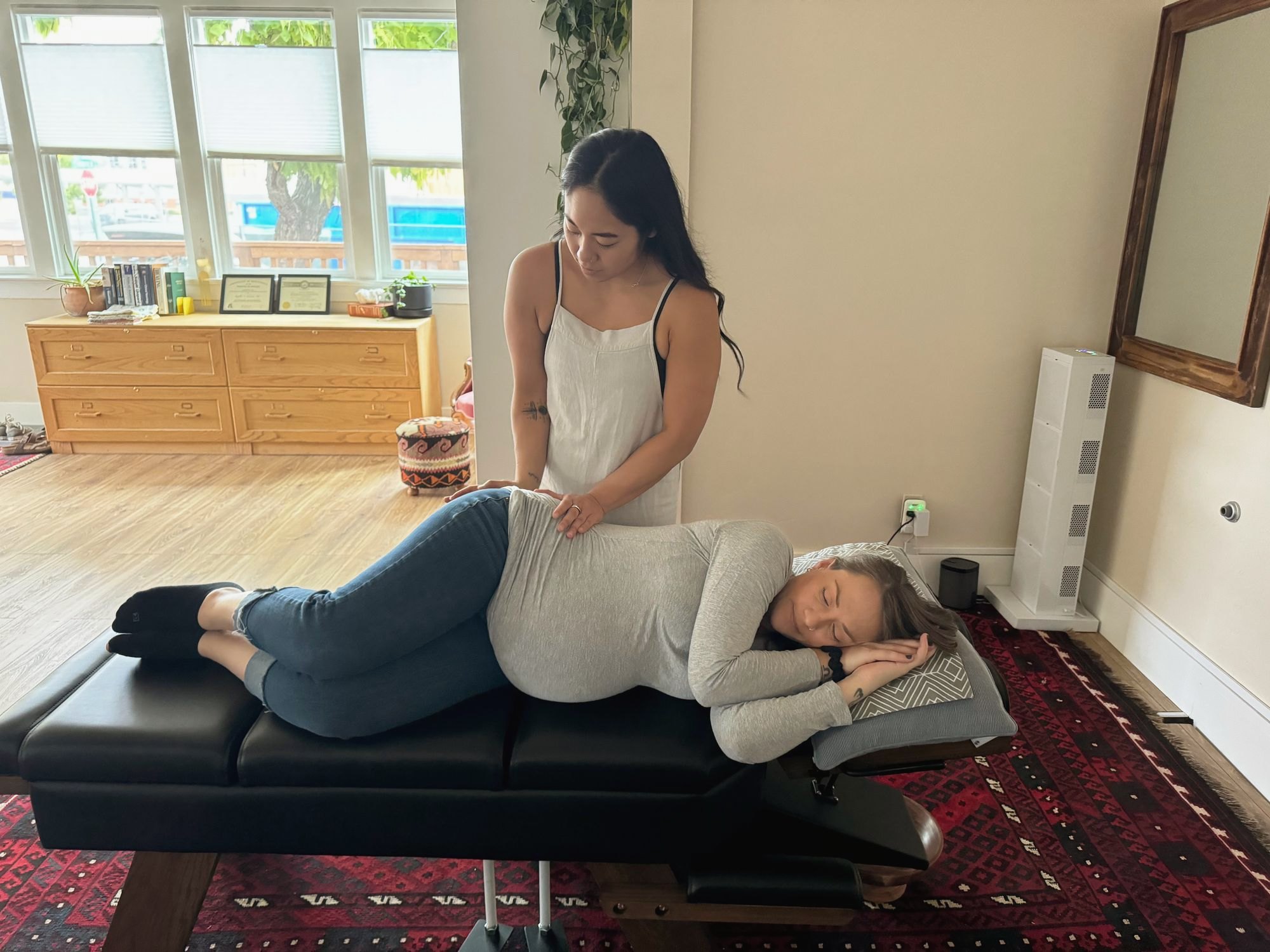 Inside the light-filled clinic, with tall windows, a patterned rug and Dr. Kaitlyn caring for a patient