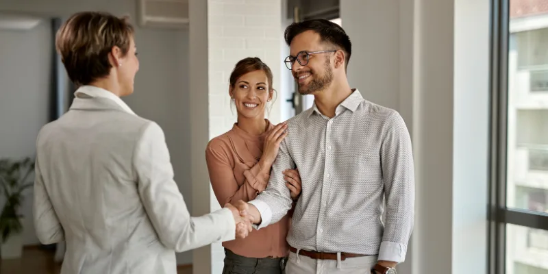 Real estate agent shaking hands with homebuyers