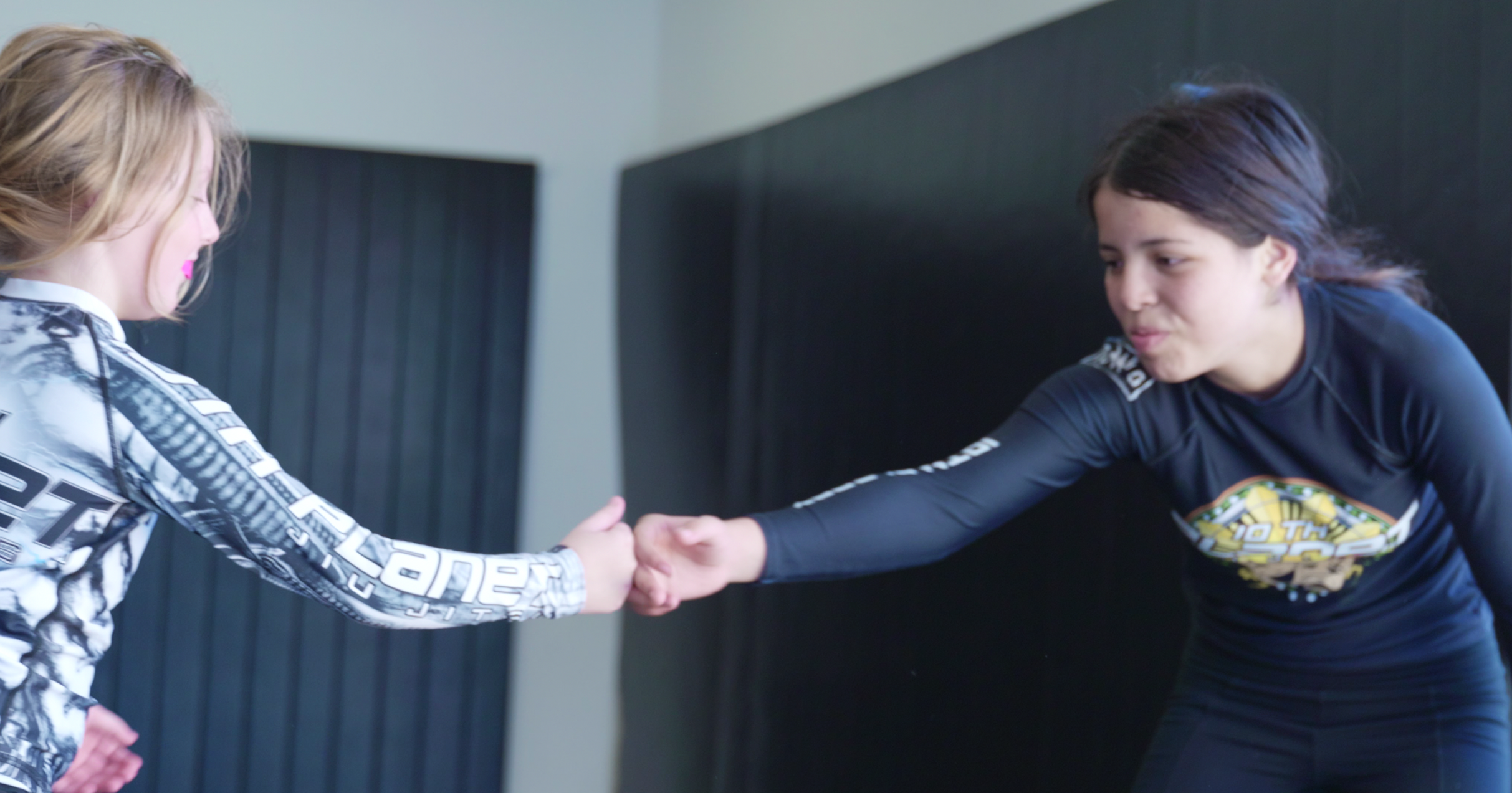 Young 10th Planet Torrance grapplers fist-bumping on the mat before rolling