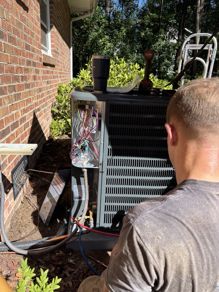 Mike Abbott checking wiring and electrical components on an outdoor AC condensing unit in Vass, NC