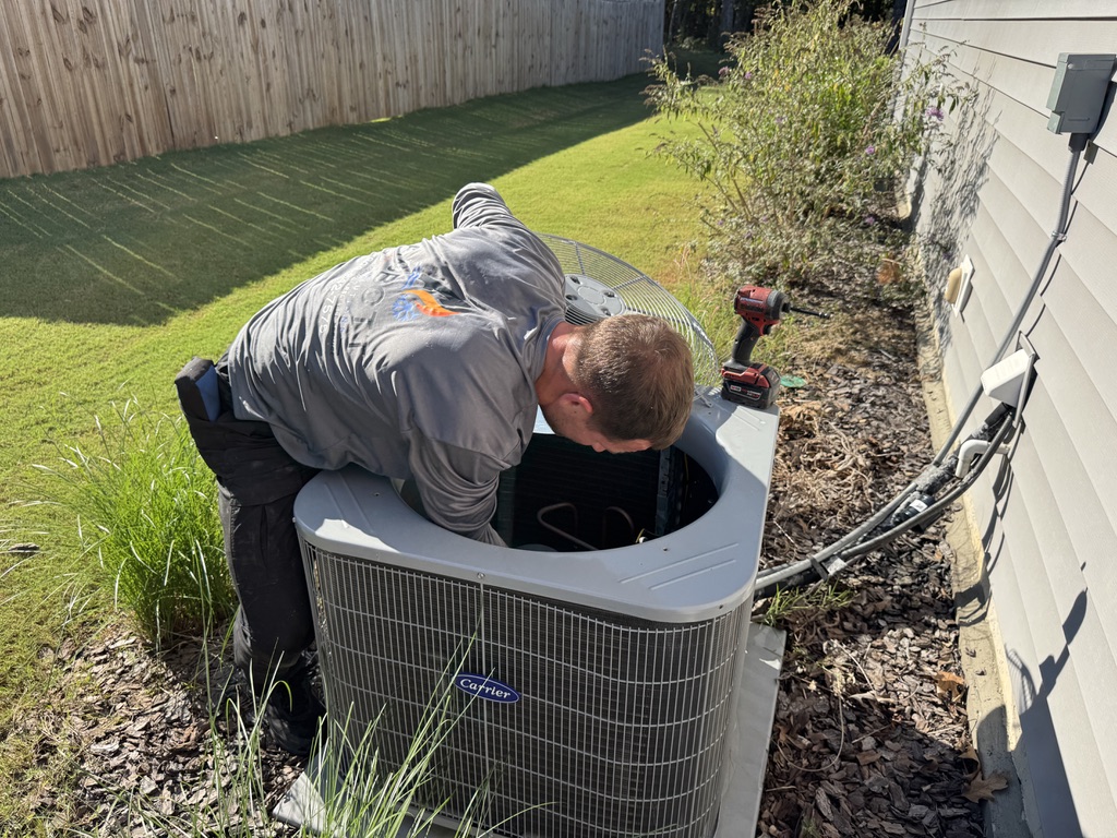 Mike Abbott inspecting outdoor Carrier air conditioning condenser during residential HVAC maintenance
