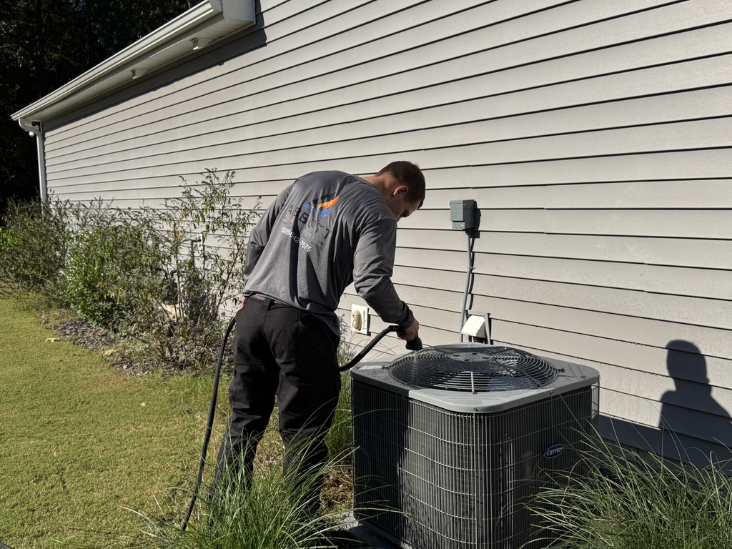 Mike Abbott performing preventive HVAC maintenance on an outdoor AC condenser in Aberdeen, NC.