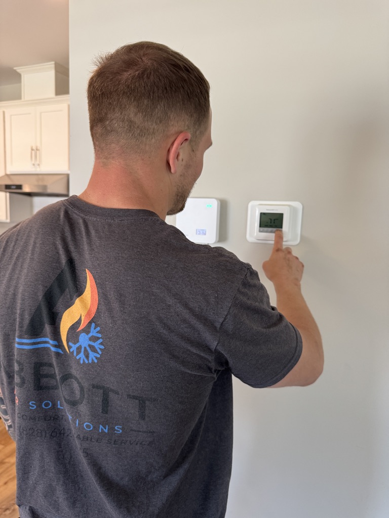 Mike Abbott servicing thermostat for HVAC maintenance