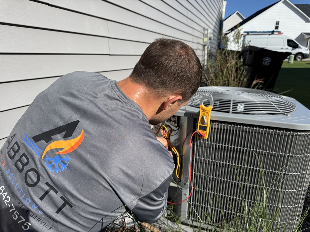 Mike Abbott testing electrical connections and voltage on an outdoor AC condenser in Whispering Pines, NC