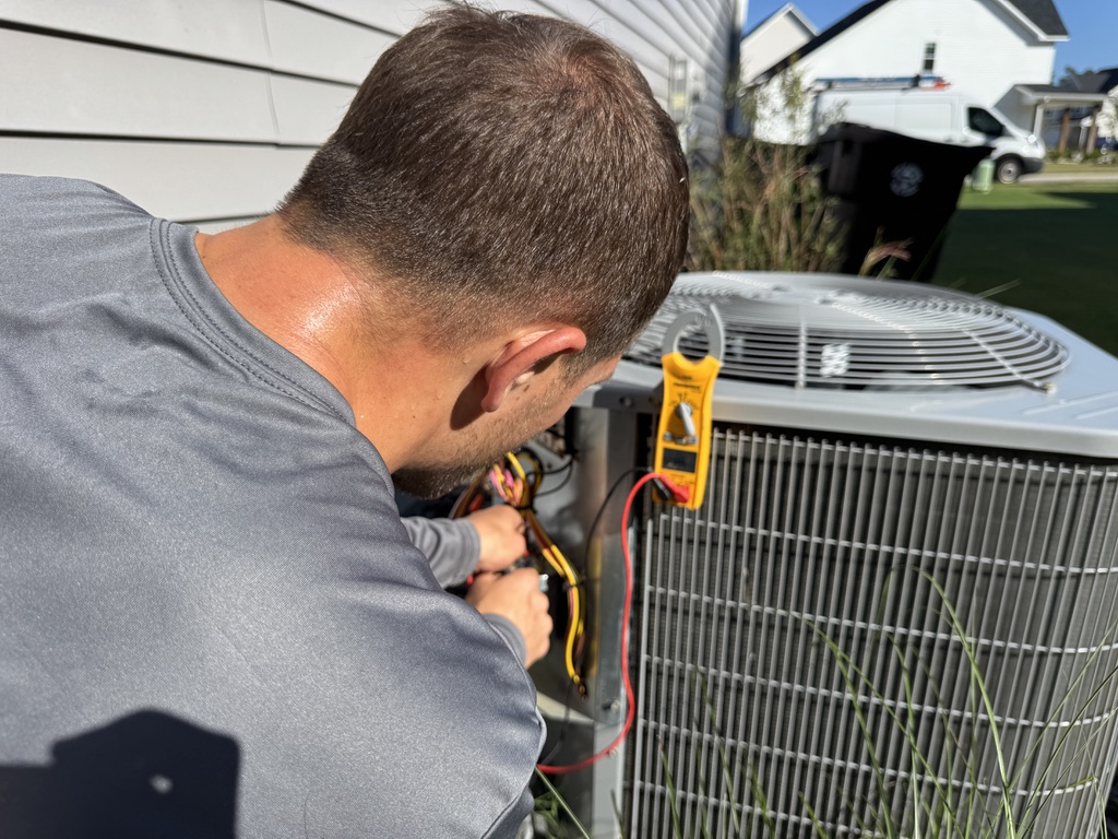 Mike Abbott inspecting outdoor condensing unit during HVAC maintenance