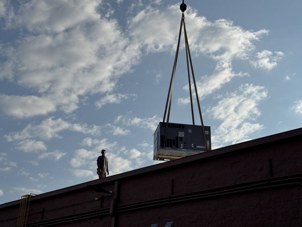 Commercial rooftop HVAC unit being lifted by crane during a system replacement in Aberdeen, NC.