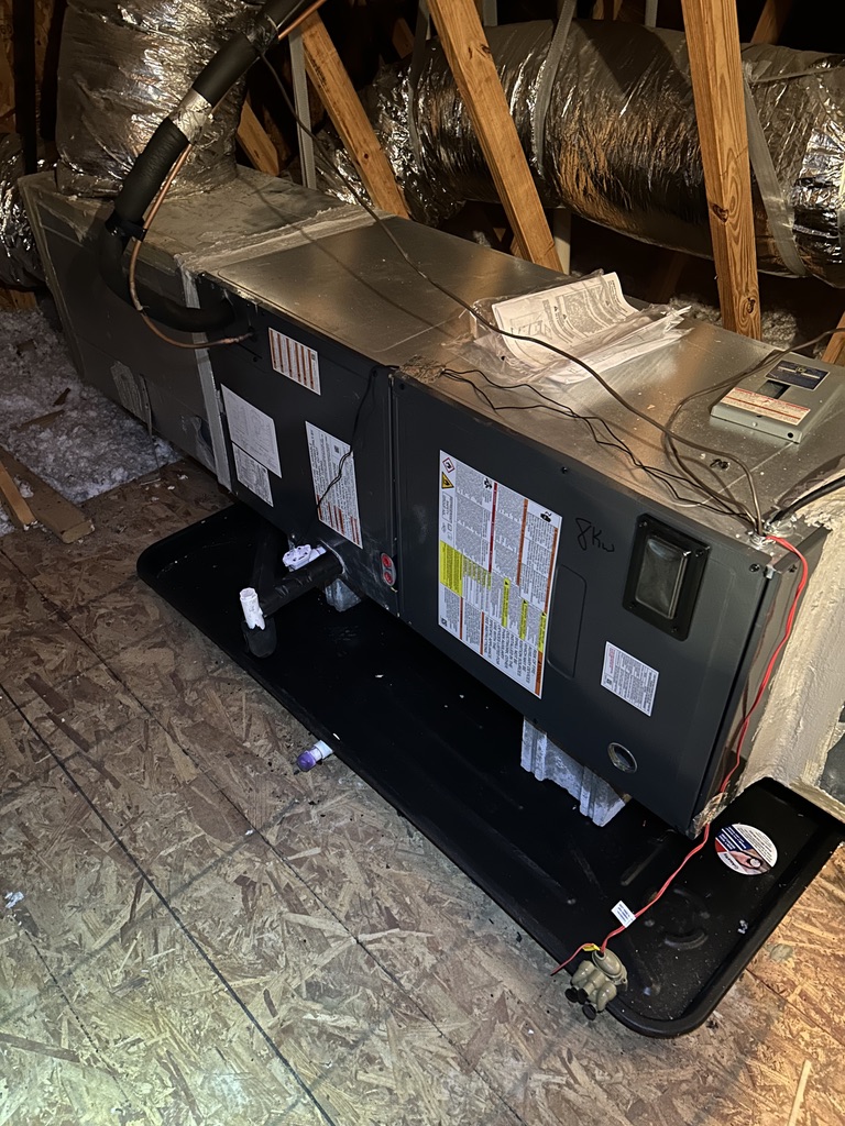 New residential HVAC air handler installed in an attic with drain pan and duct connections
