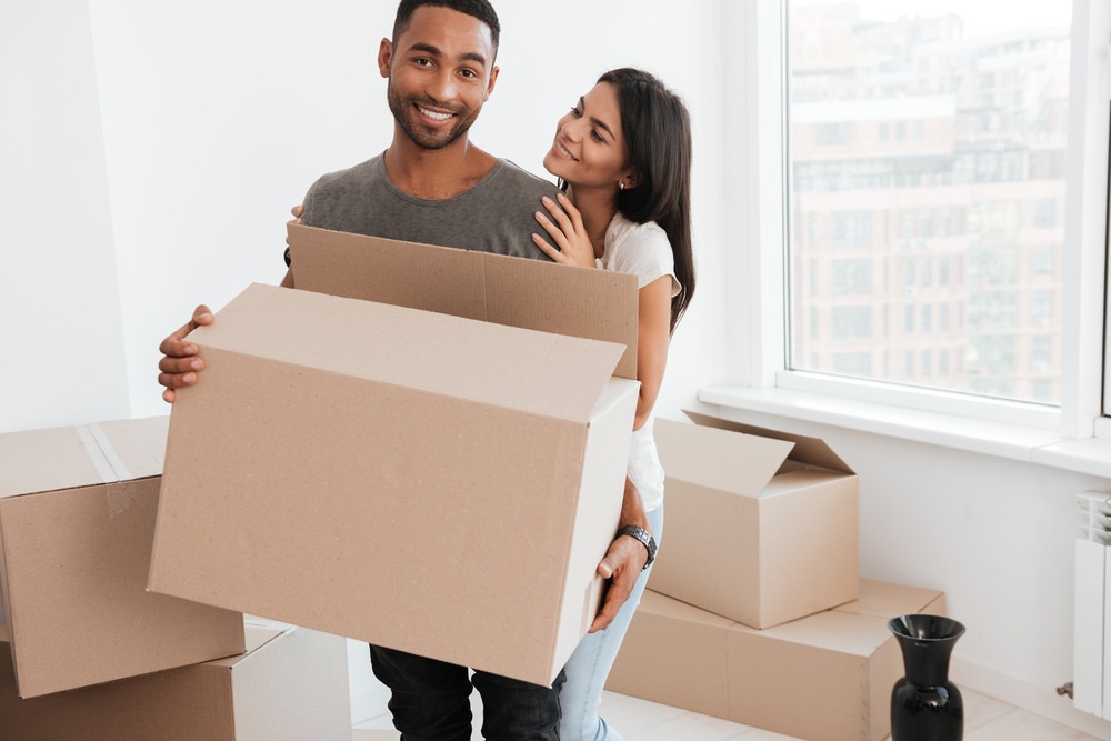 graphicstock-loving-couple-standing-near-unpacked-boxes-woman-hugging-man-and-look-at-him-man-holding-box-in-hands-while-looking-at-camera_BLWzZY7dnx_PMNW