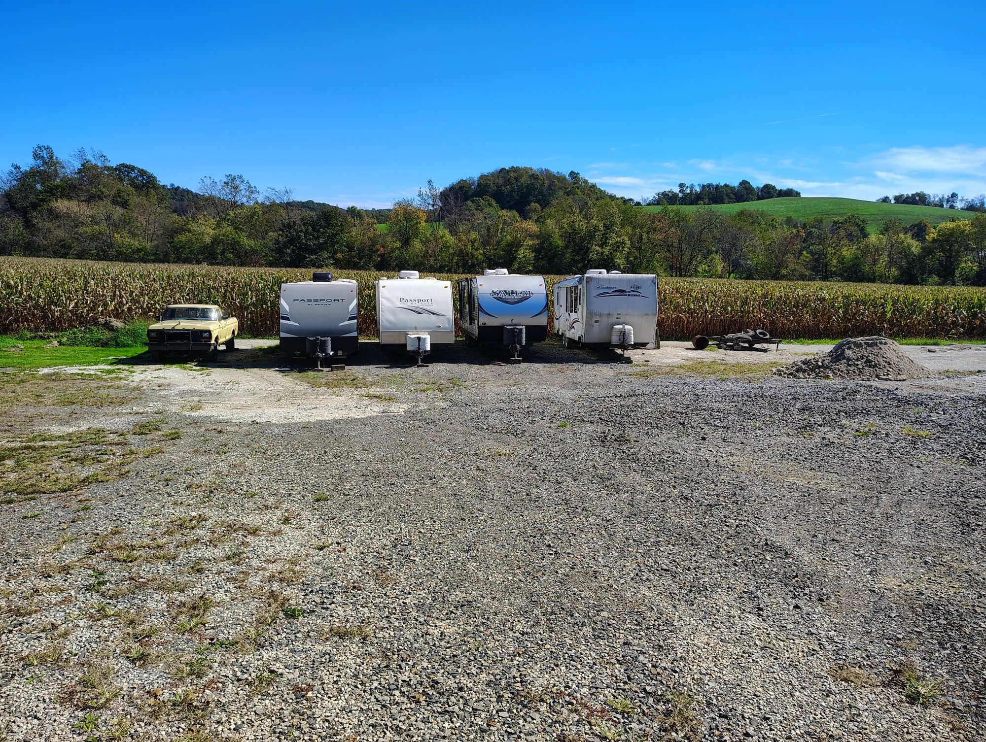 Parked campers and RVs along the tree line and cornfield at Ragersville Storage LLC