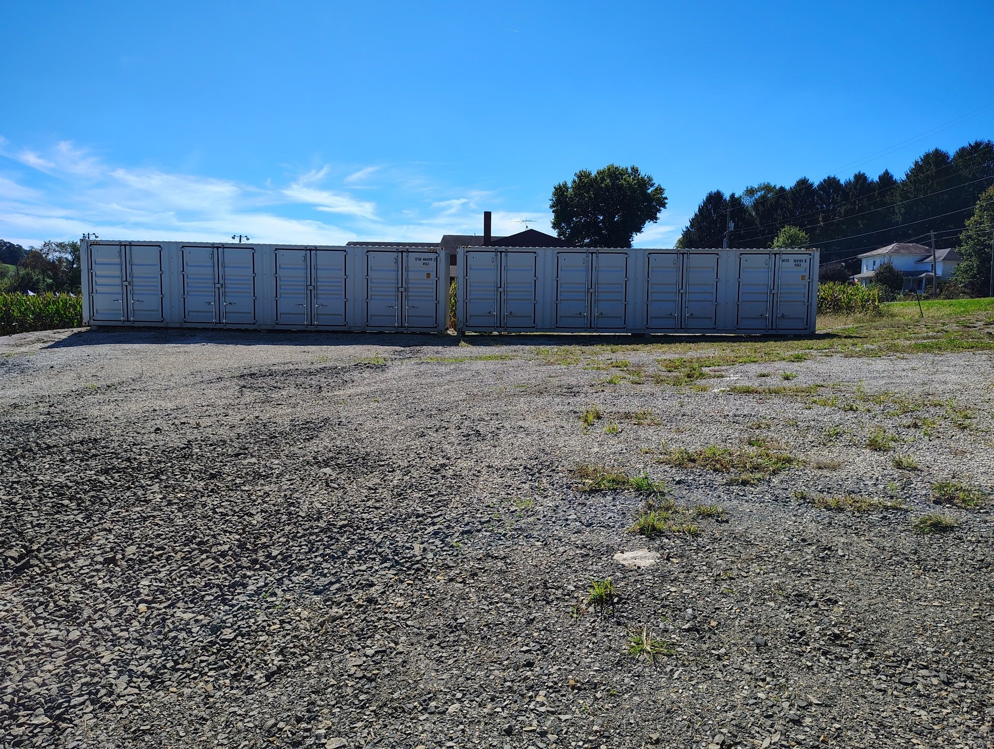Wide landscape view showing the full row of brand-new storage units on gravel lot