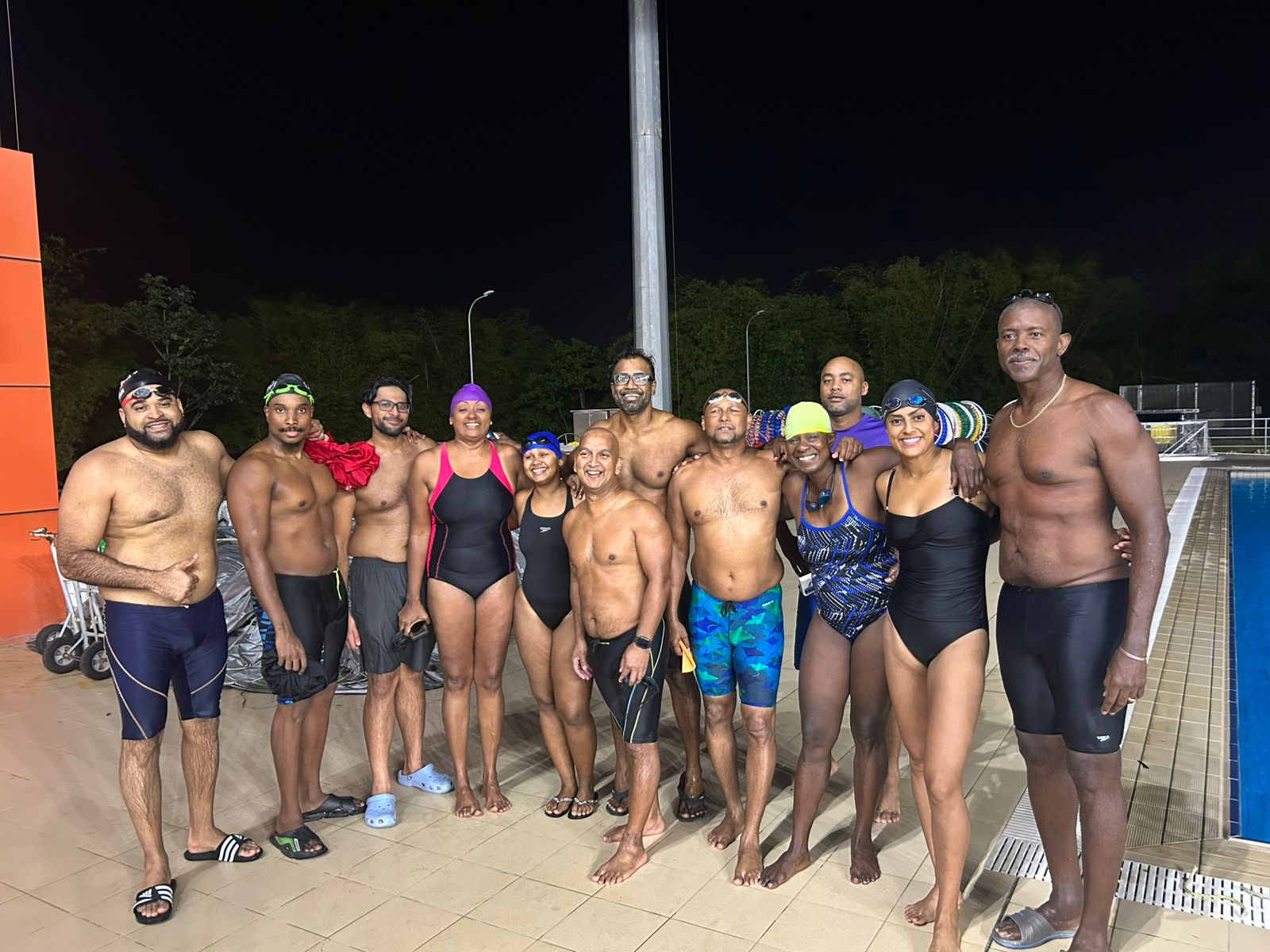 Adult swimming squad training at night by the pool deck