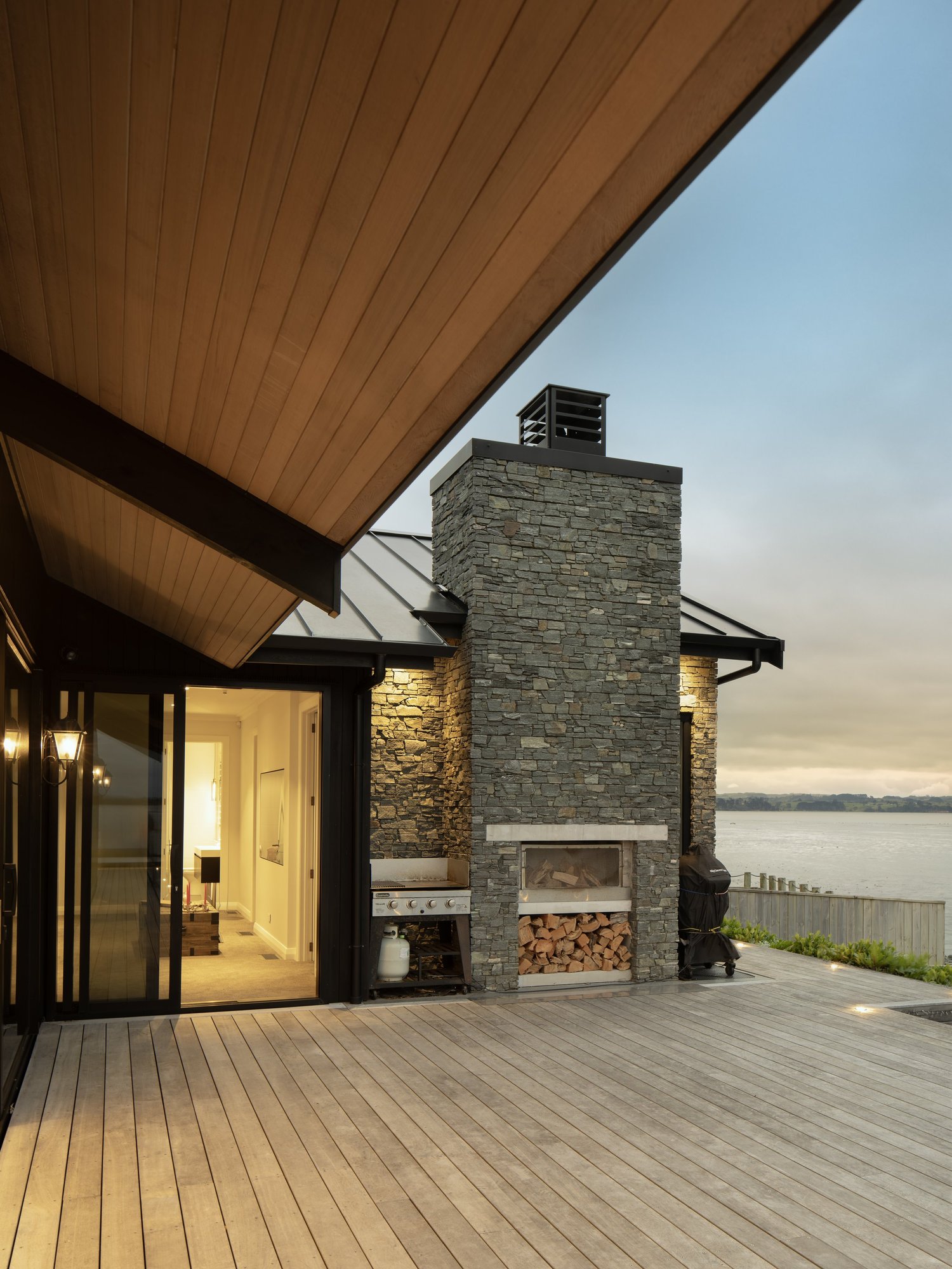 Deck and stone fireplace looking over the water at the Clarks Beach new build