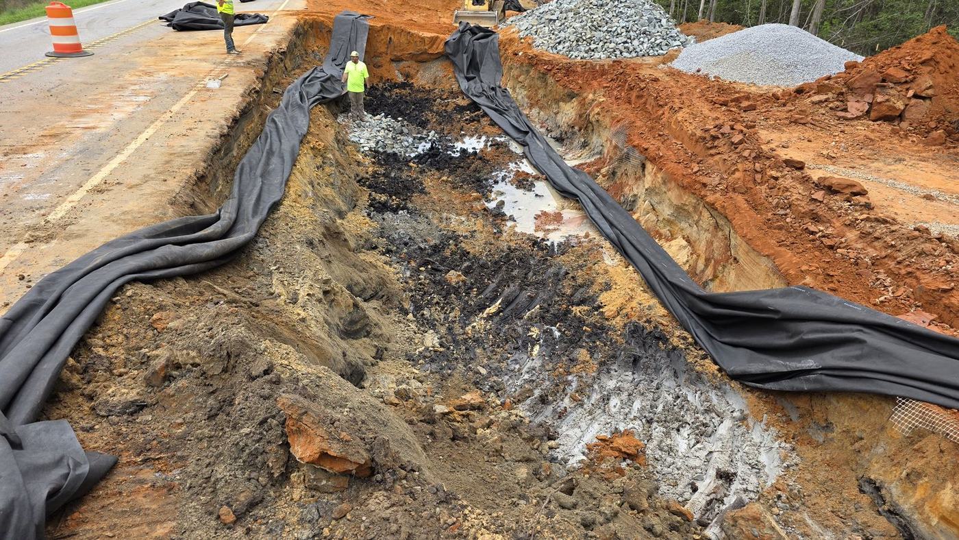 A drainage trench lined with erosion-control matting beside a state highway