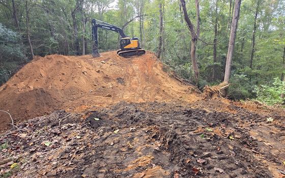 An excavator digging into a bank of South Carolina red clay