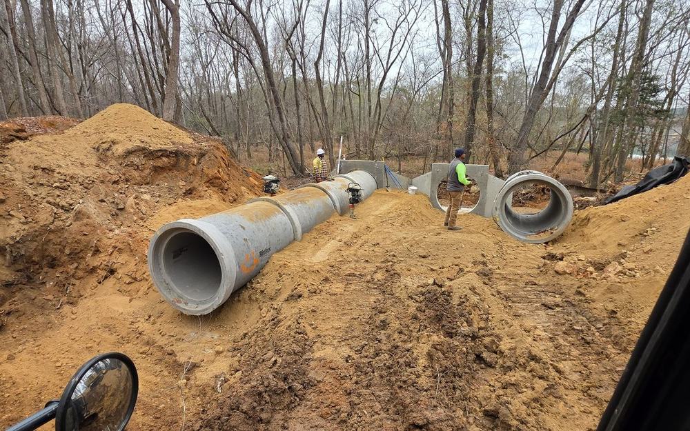 Large concrete storm drain sections staged beside an open trench