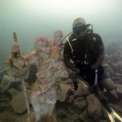 Diver next to submerged patron saint statue with a staff