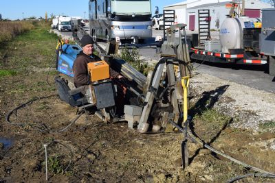 Operator standing at the control panel of a compact horizontal directional drill on a graded outdoor jobsite