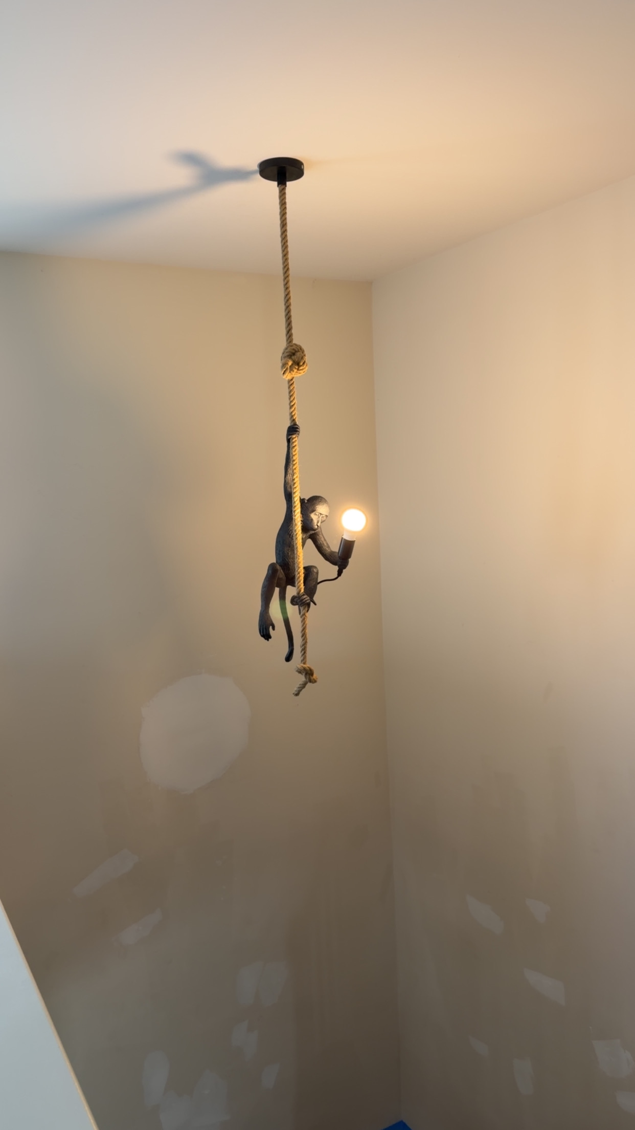 Artisan sculpted monkey climbing natural hemp rope pendant light with exposed filament bulb installed by Wavecrest Electric