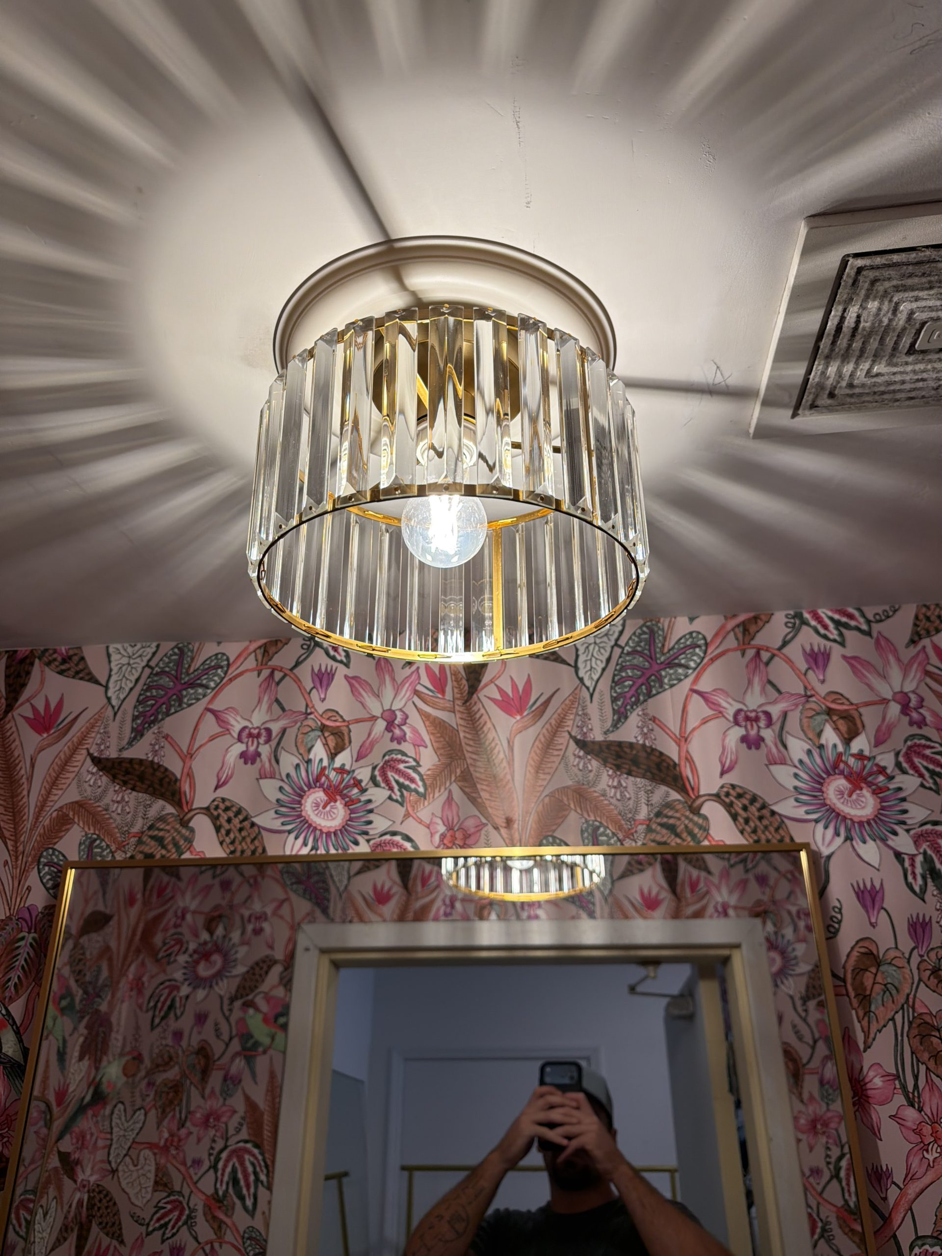 Fluted crystal prism and brass flush mount ceiling fixture installed over decorative powder room vanity by Wavecrest Electric