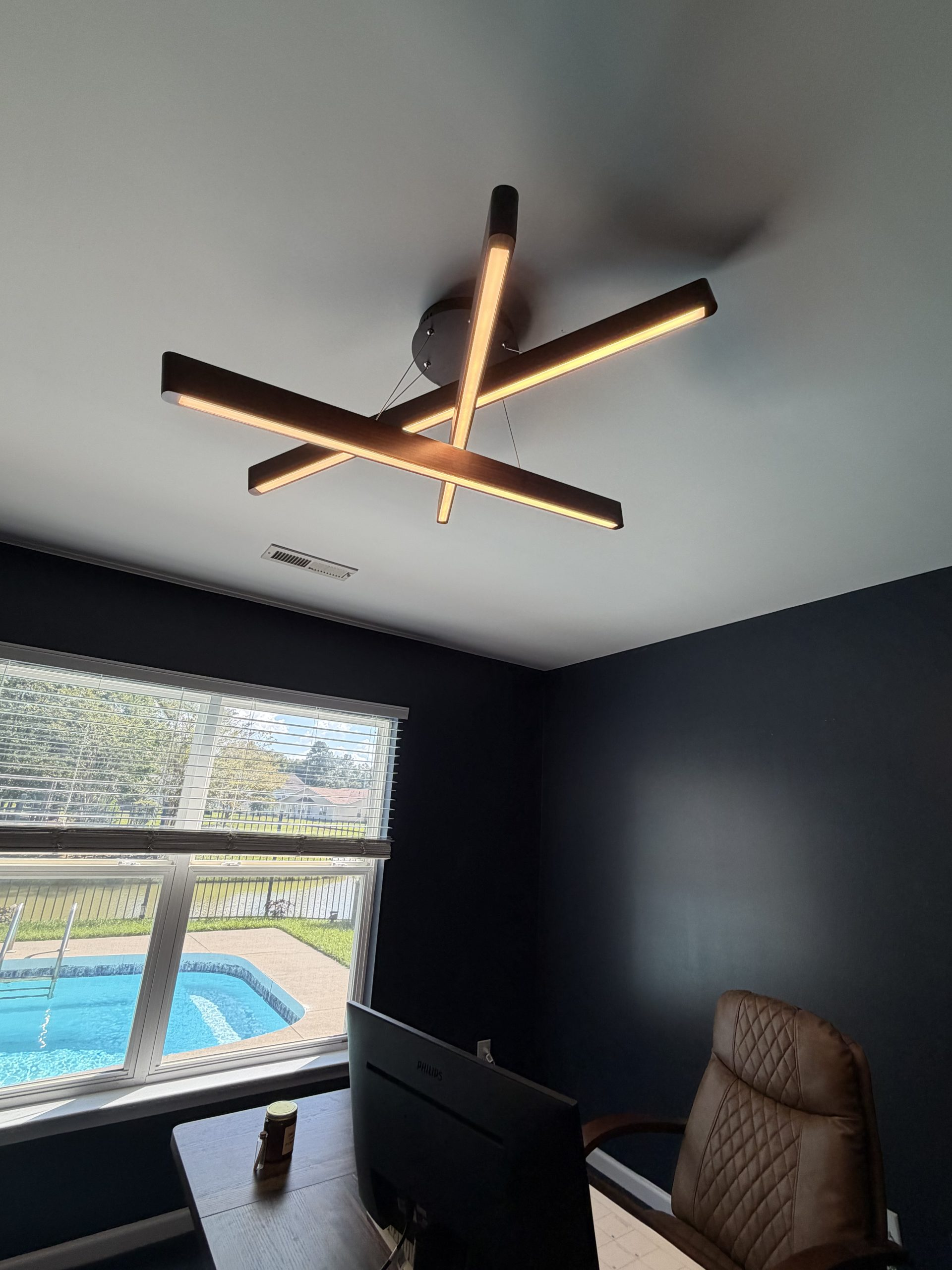 Modern geometric overlapping linear LED chandelier installed in luxury home office overlooking pool by Wavecrest Electric
