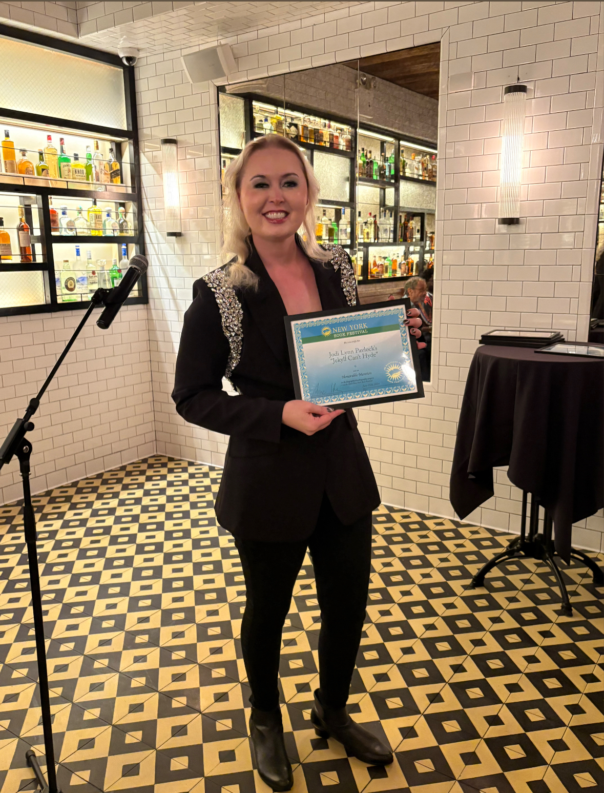 Jodi Lynn Pavlock holding her New York Book Festival award certificate for Jekyll Can’t Hyde.