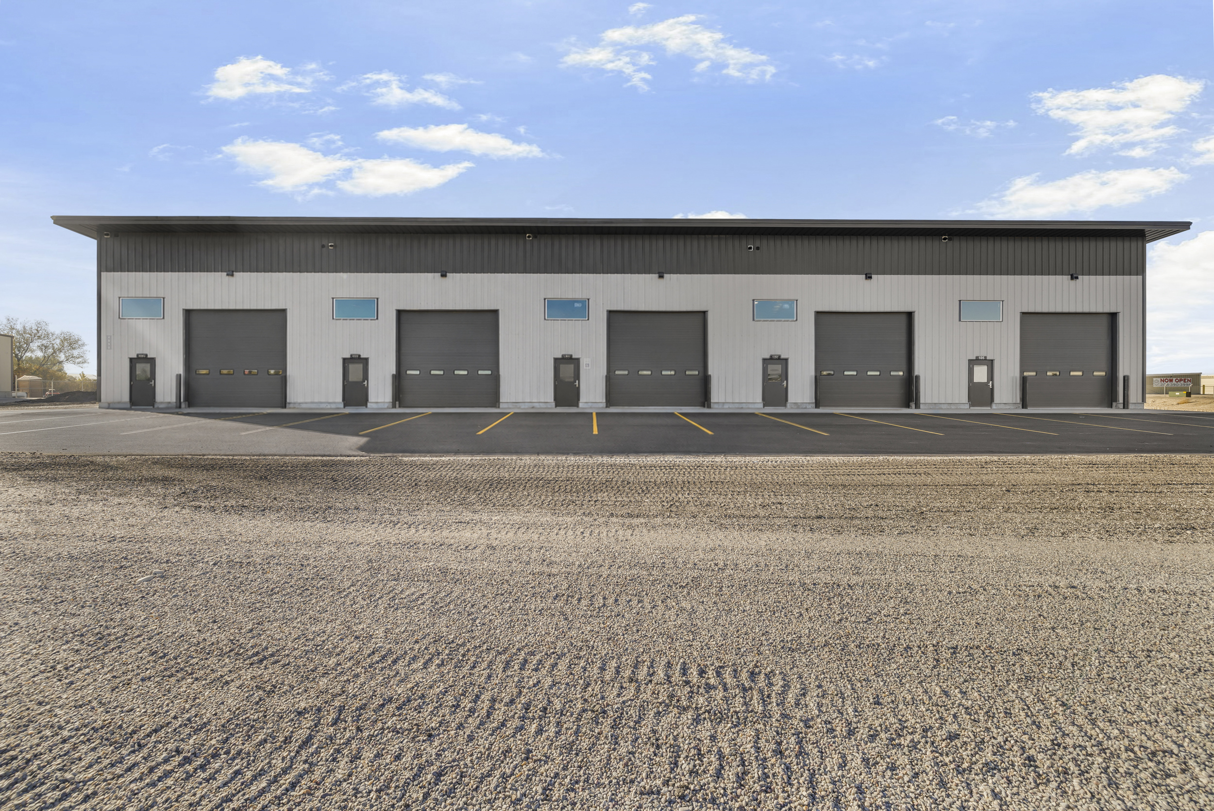 Front-on exterior view of Rexburg Shop Space showing roll-up bay doors and asphalt parking stalls