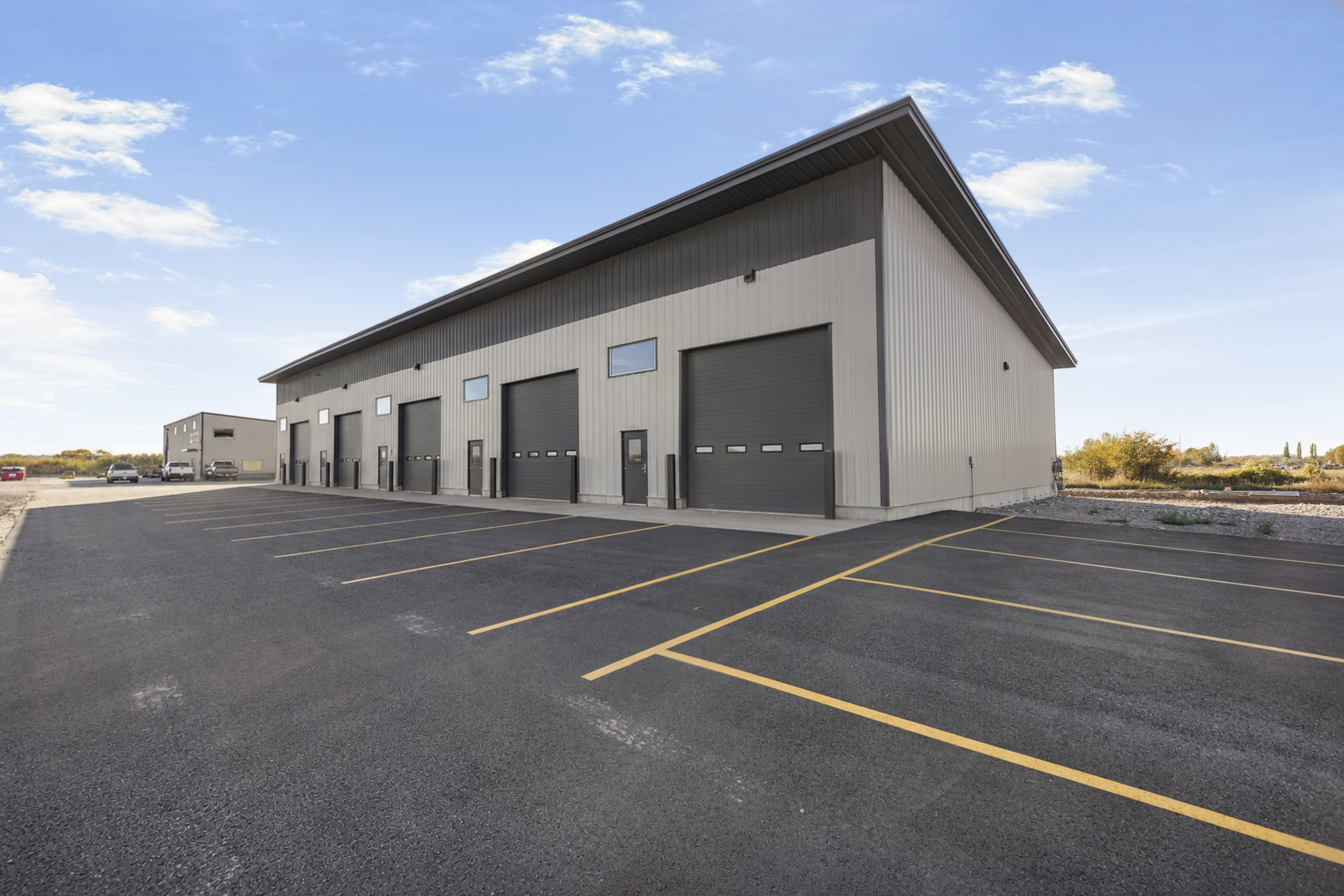 Perspective exterior view of shop bays showing clean asphalt parking lot and building profile