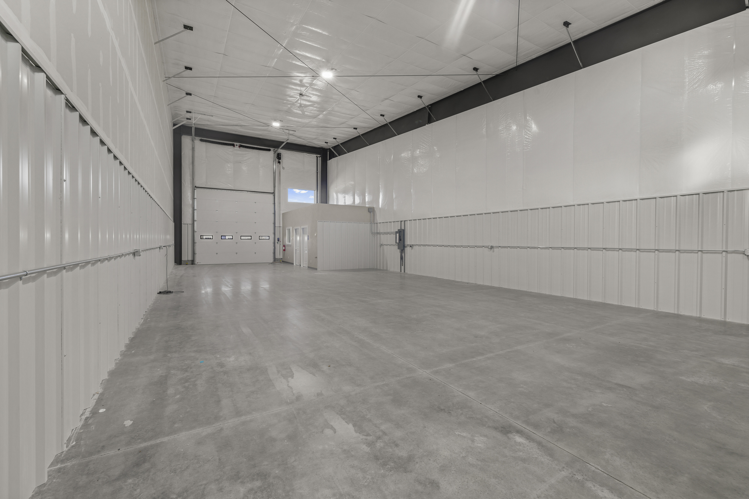 Drive-in roll-up door inside 2,100 sq ft bay with sealed concrete floor and private office structure
