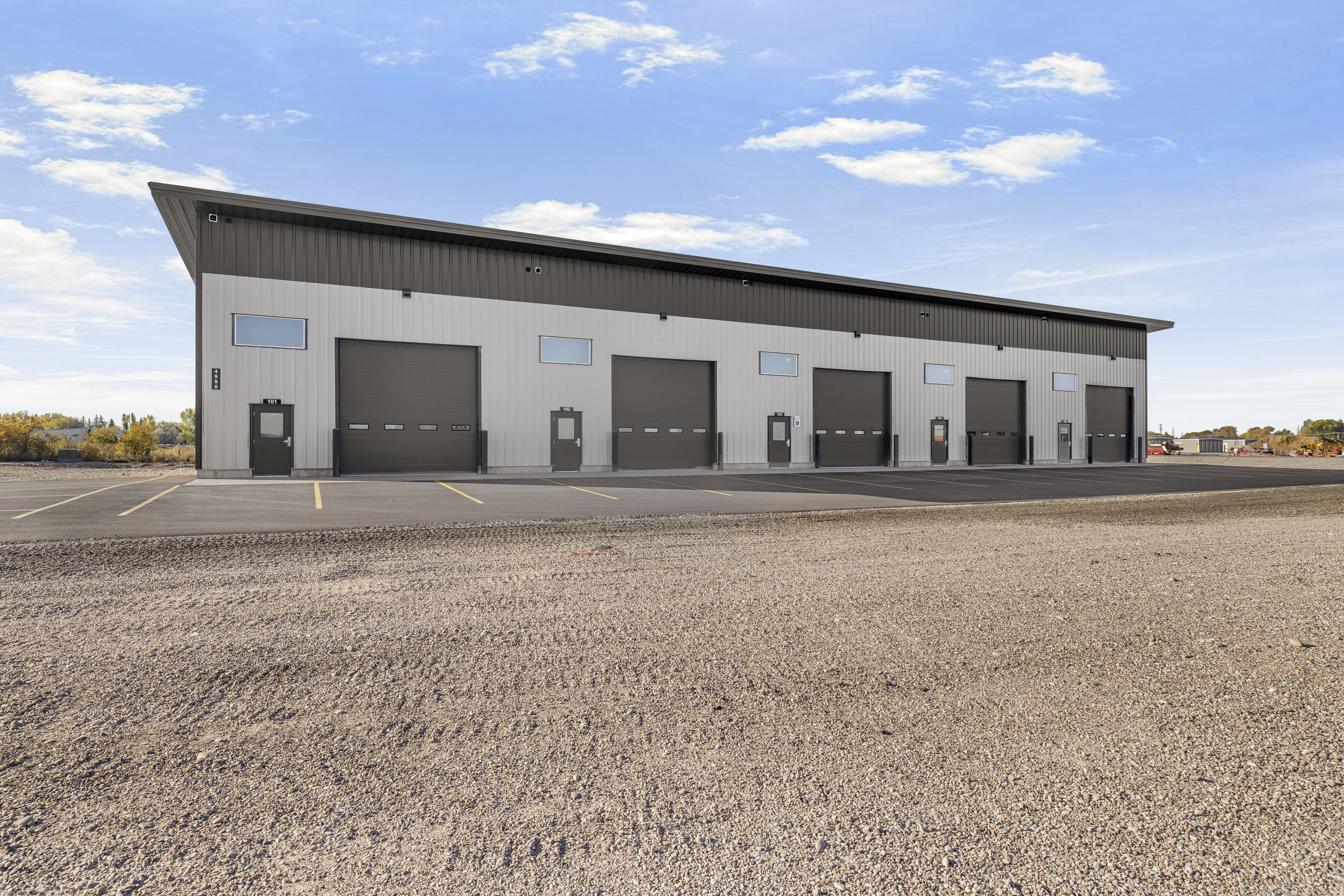 Three-quarter exterior view of Rexburg Shop Space showing roll-up bay doors, entry doors, and parking lot