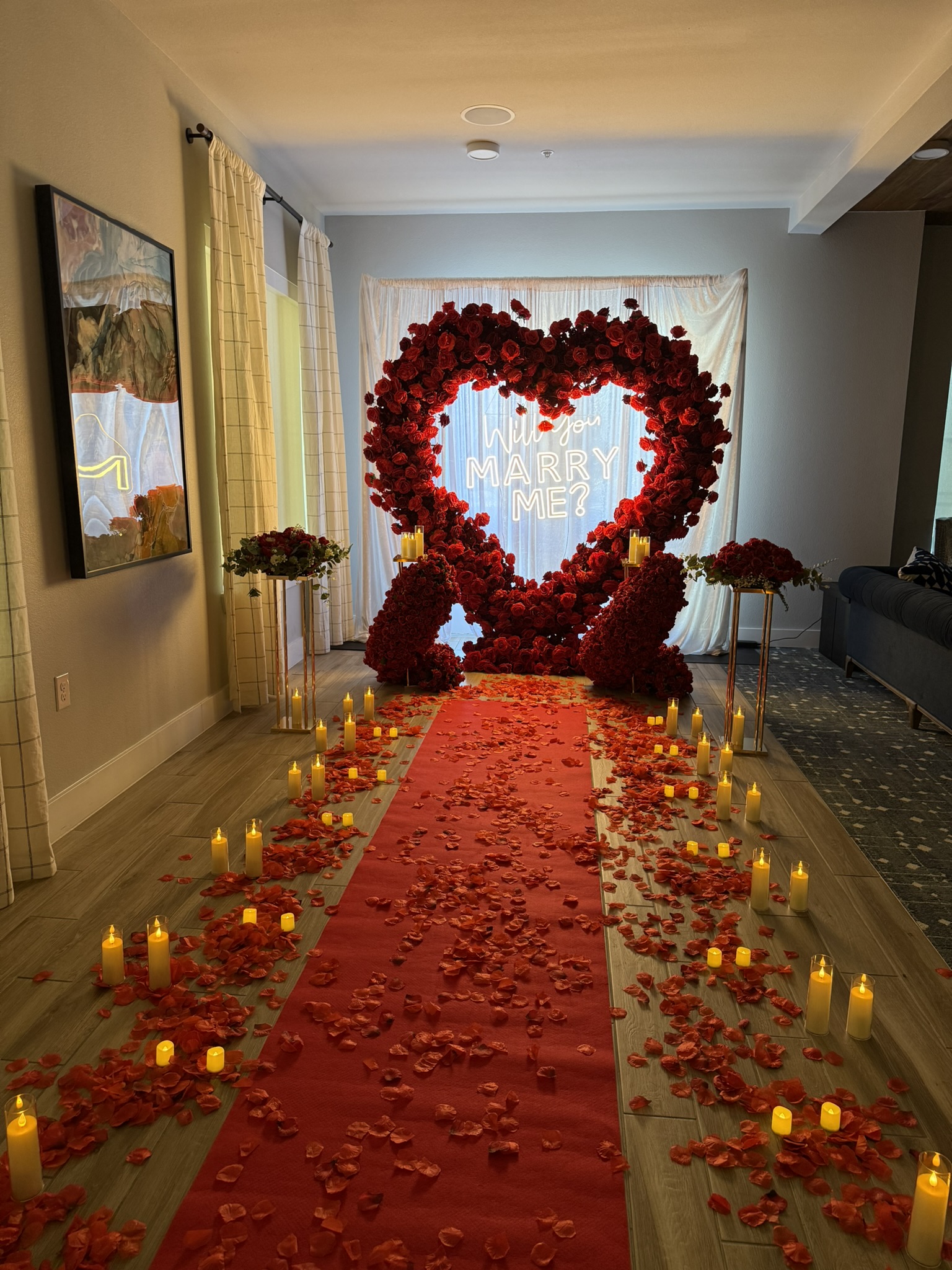 Romantic candlelit rose petal runner and gold floral stands leading to luxury proposal heart arch