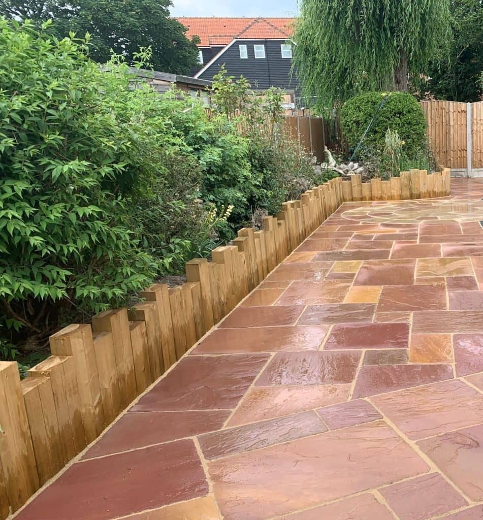 Natural Indian sandstone patio with a newly laid curved lawn and timber edging in Basildon