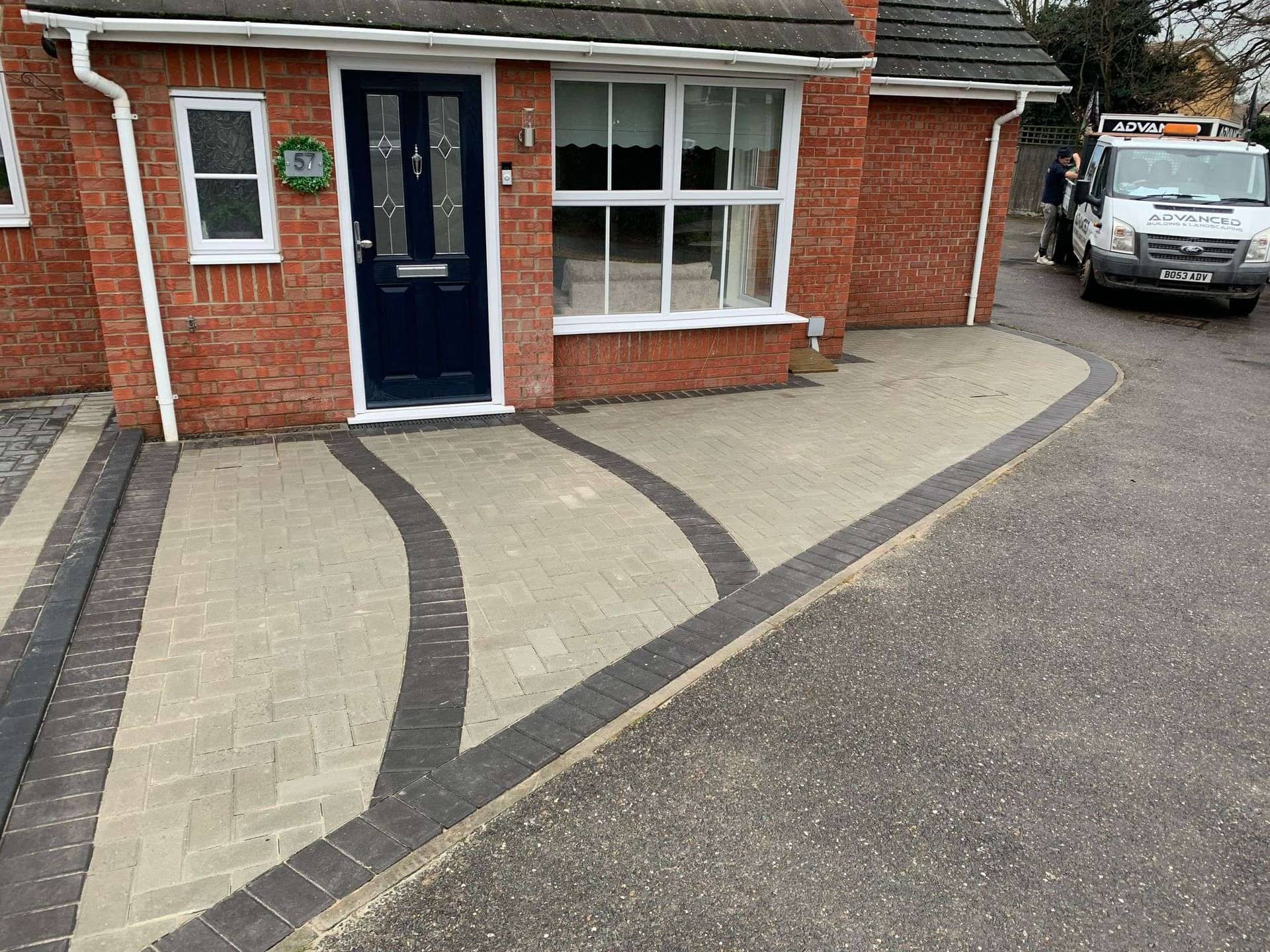Block paved driveway with curved black and beige tiles and Advanced Building & Landscaping van