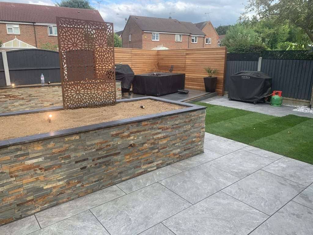 Composite decking terrace with hot tub surround, laser-cut screens and cedar fencing in Billericay
