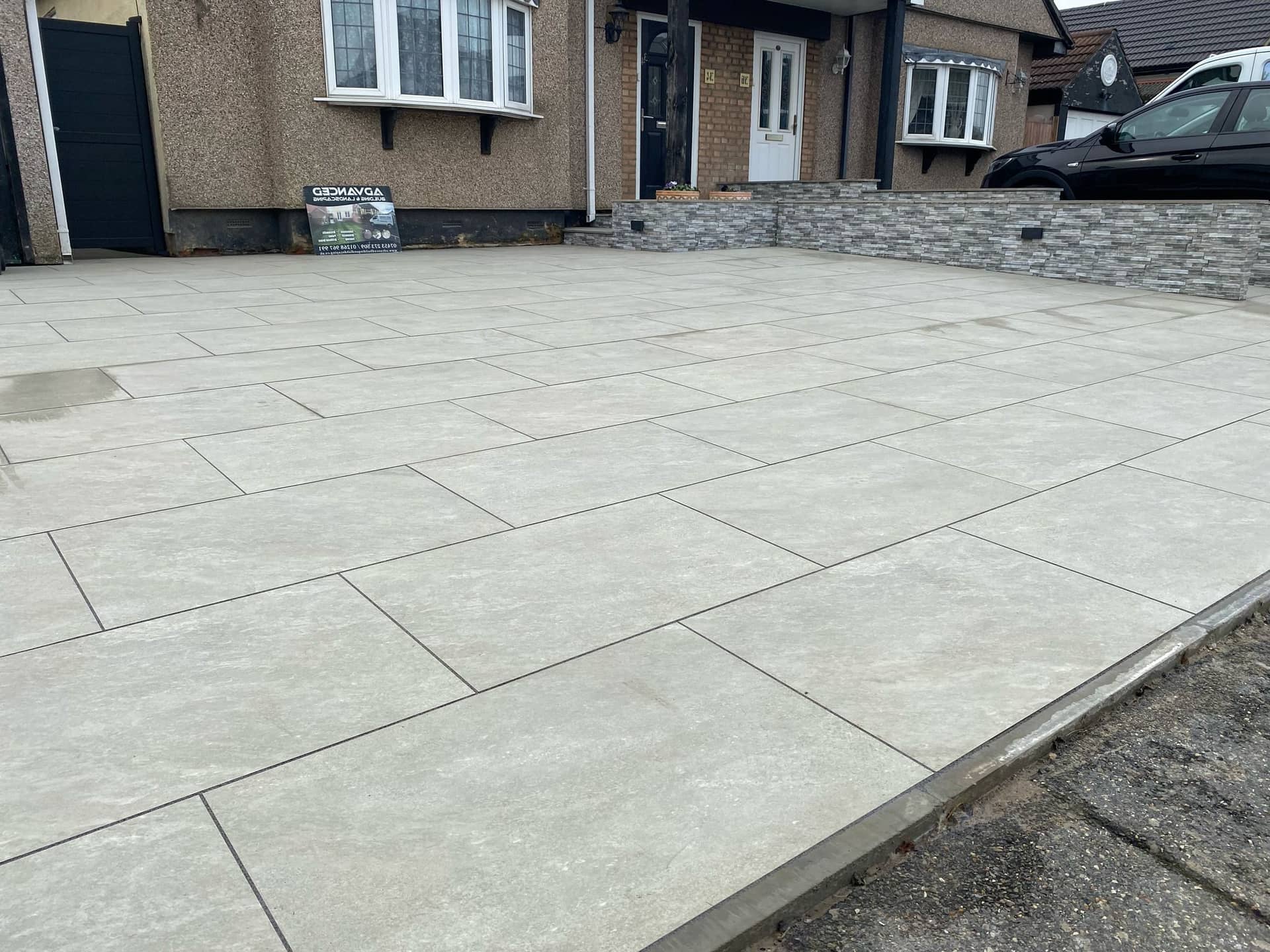 Completed paved driveway in front of house with Advanced Building & Landscaping sign in Essex