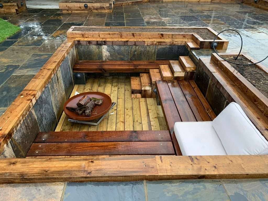 Timber sunken seating area with built-in firepit and sleeper planters in Basildon